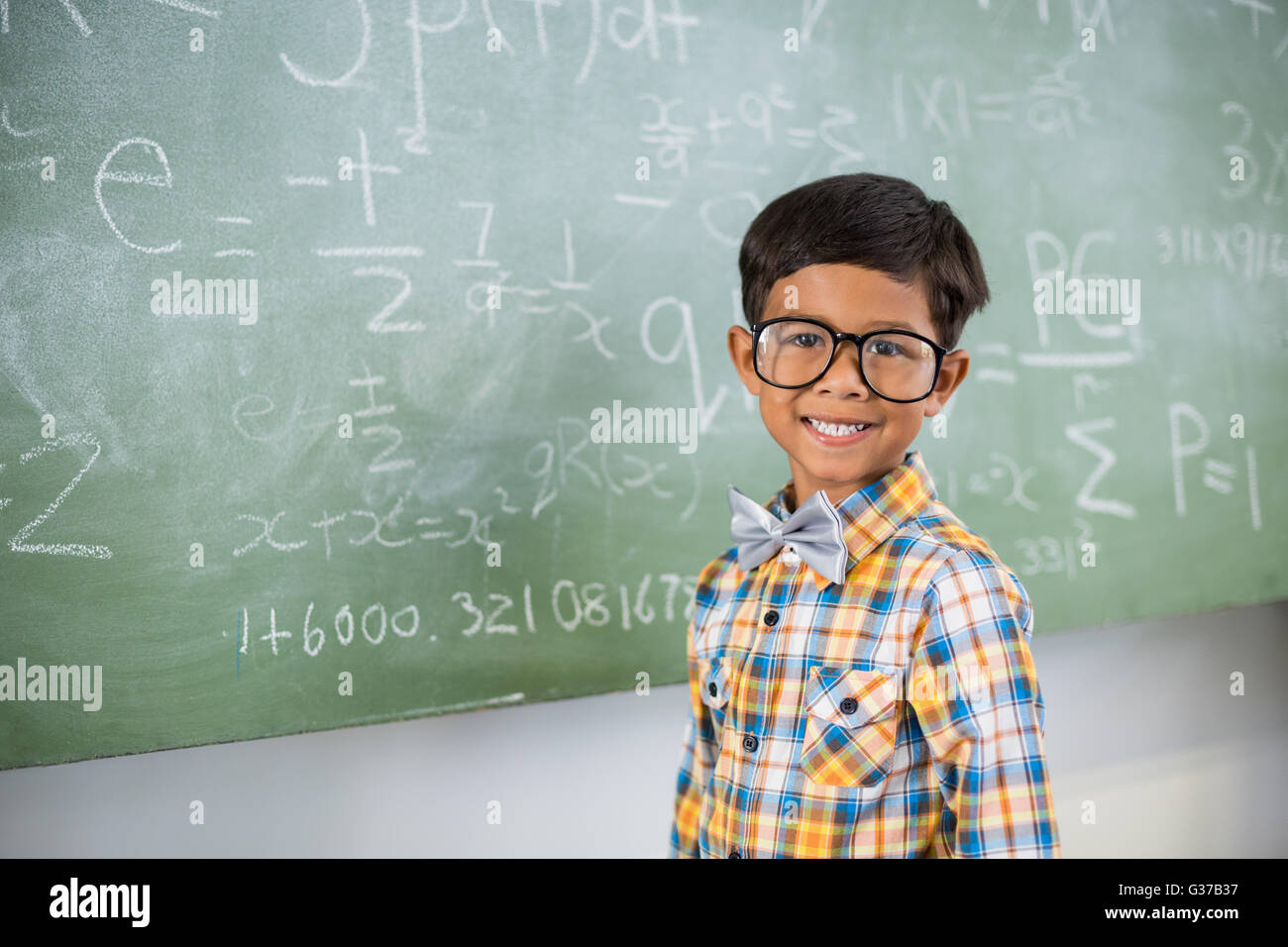 Porträt von Schuljunge lächelnd gegen Tafel im Klassenzimmer Stockfoto