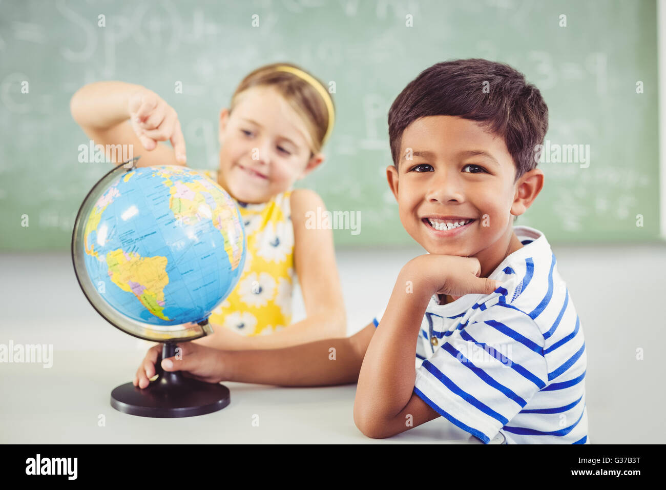 Glückliche Schulkinder mit Globus im Klassenzimmer Stockfoto