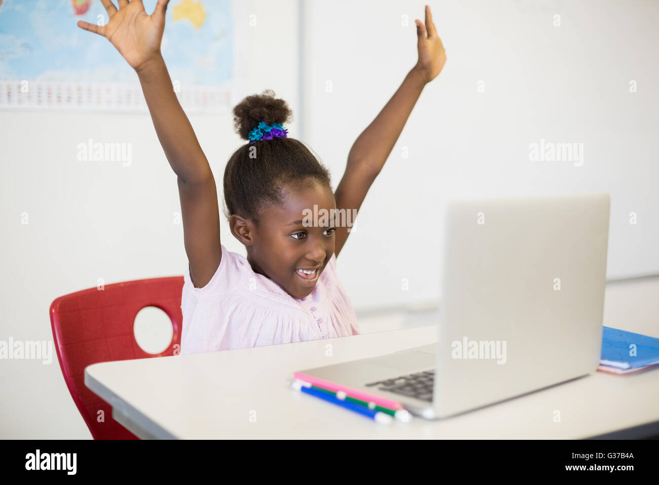 Aufgeregt Schulmädchen mit Laptop im Klassenzimmer Stockfoto