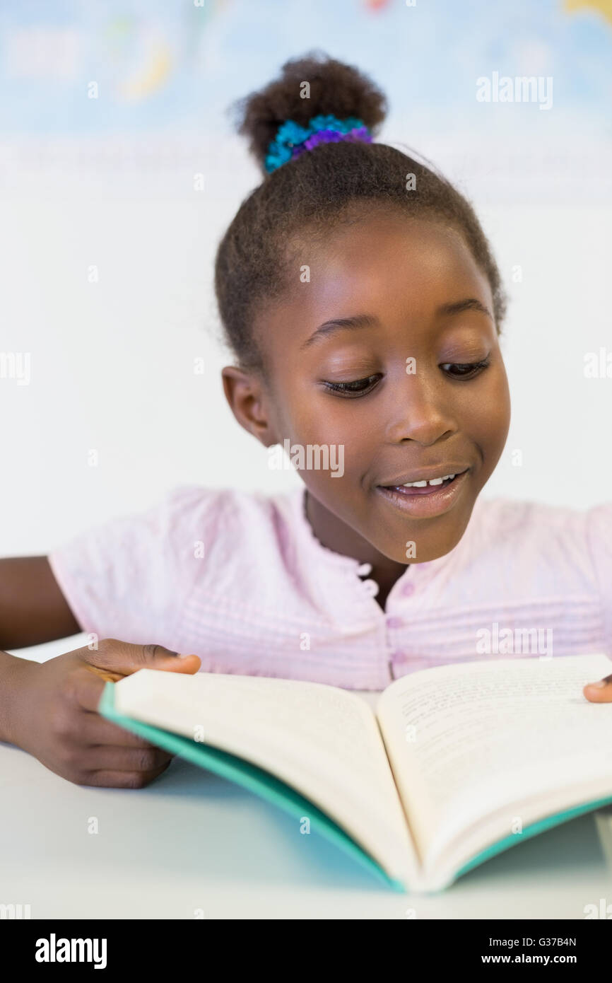 Lächelnd Schule Mädchen Lesebuch im Klassenzimmer Stockfoto