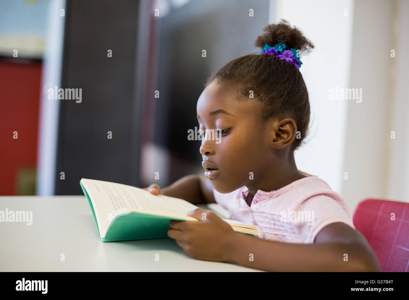 Schule Mädchen Lesebuch im Klassenzimmer Stockfoto