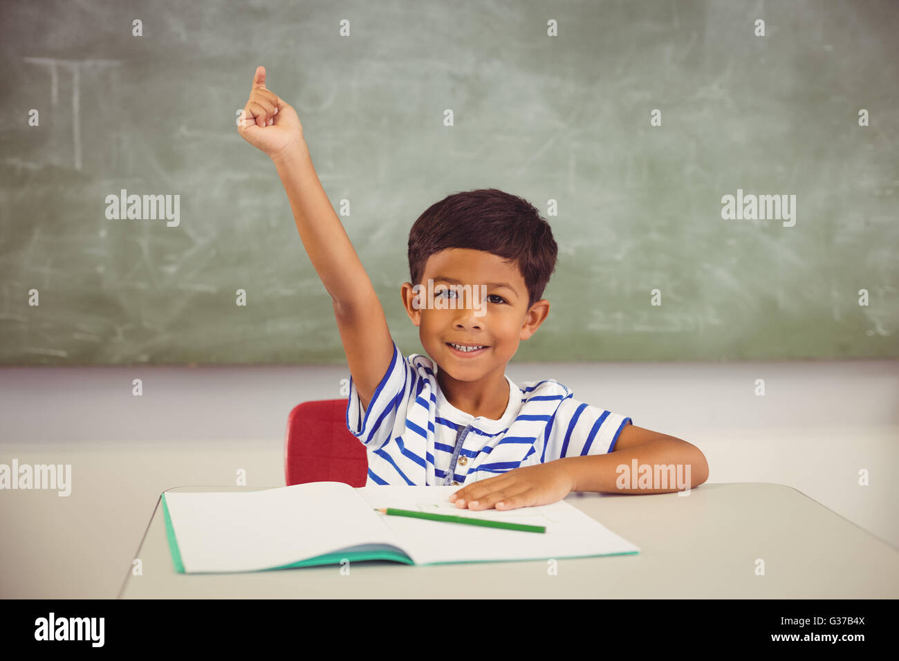 Porträt von Schuljunge hob seine Hand im Klassenzimmer Stockfoto