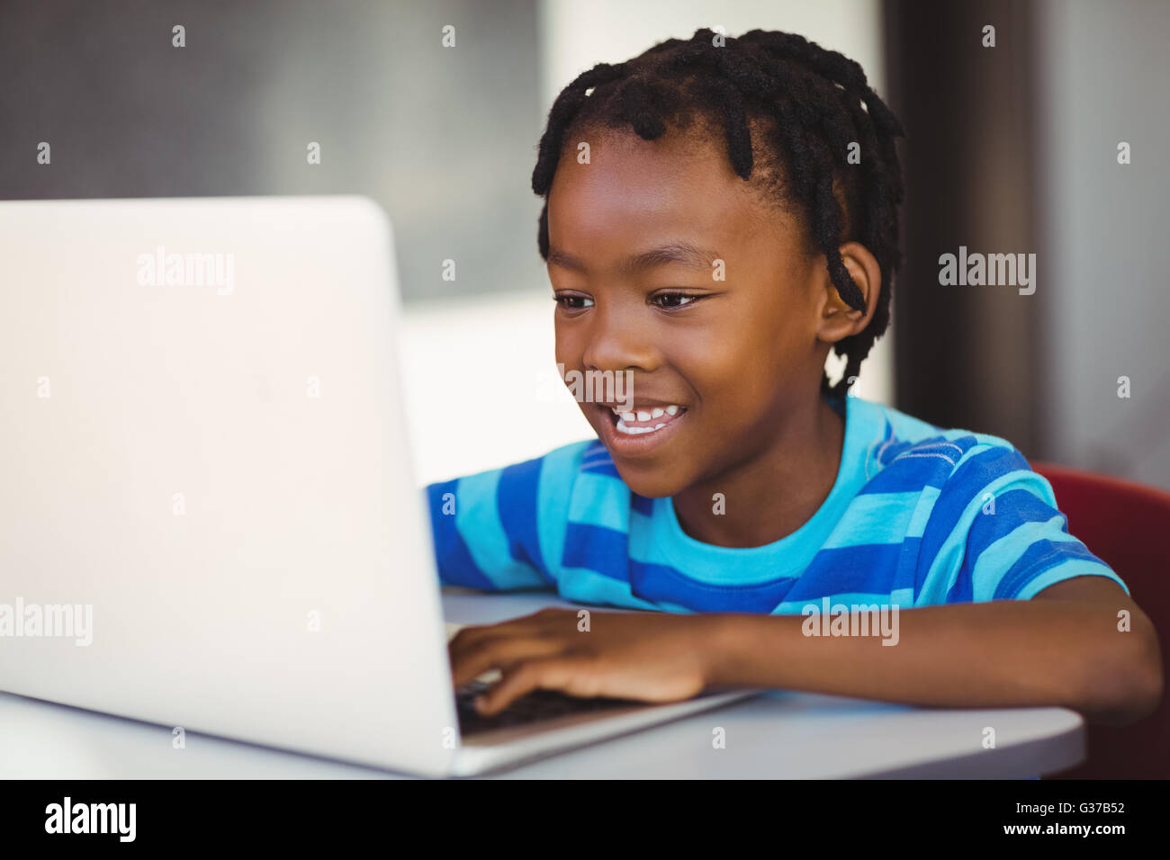 Lächelnde Schuljunge mit Laptop im Klassenzimmer Stockfoto