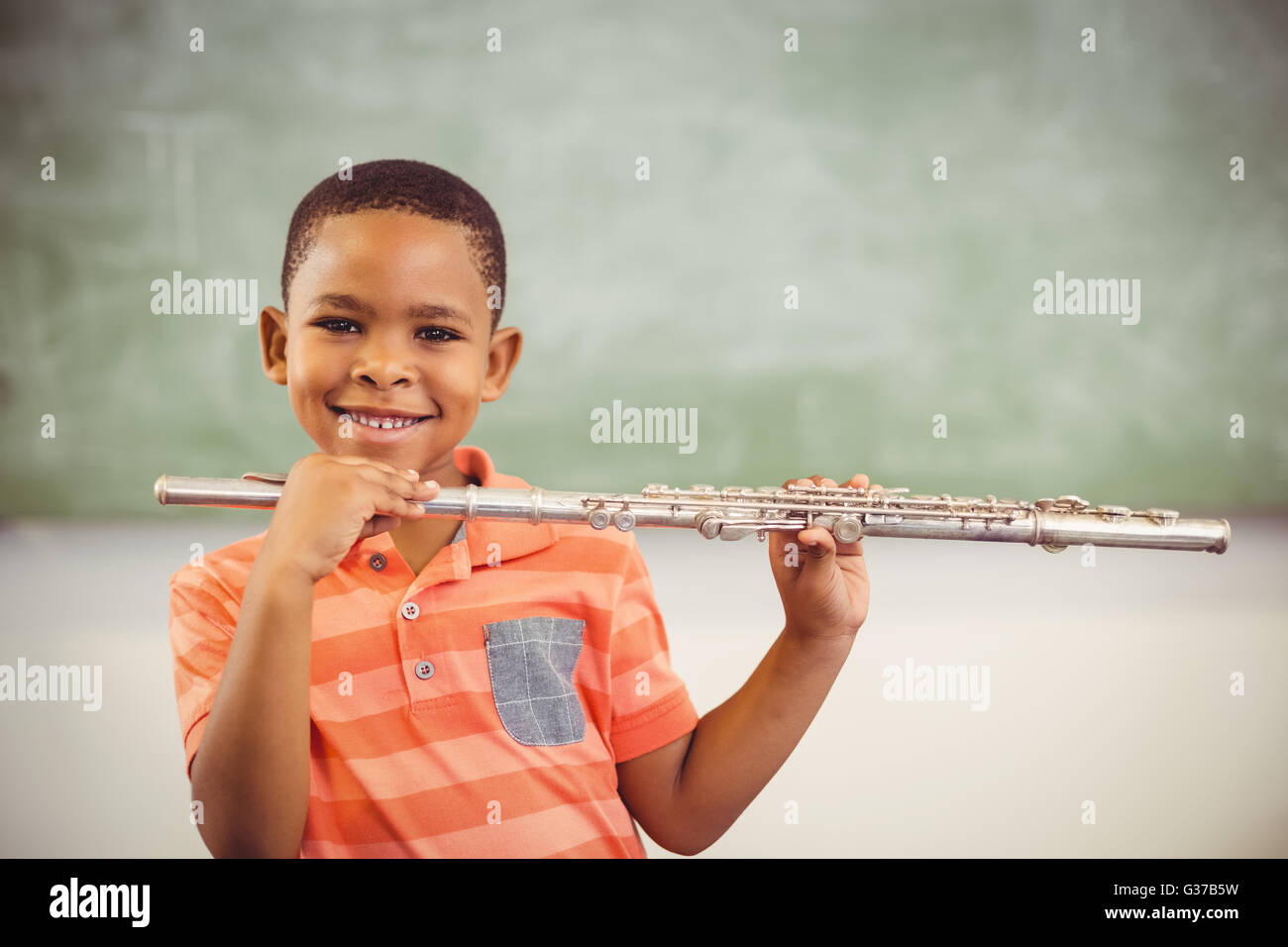 Porträt von lächelnden Schuljunge Flötenspiel im Klassenzimmer Stockfoto