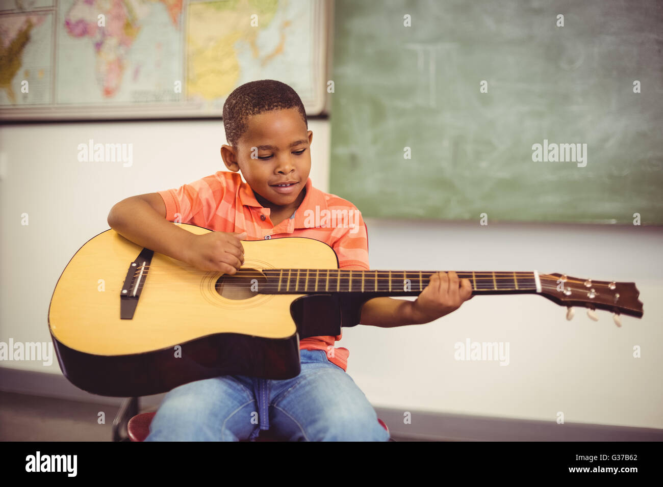 Schuljunge Gitarre spielen im Klassenzimmer Stockfoto