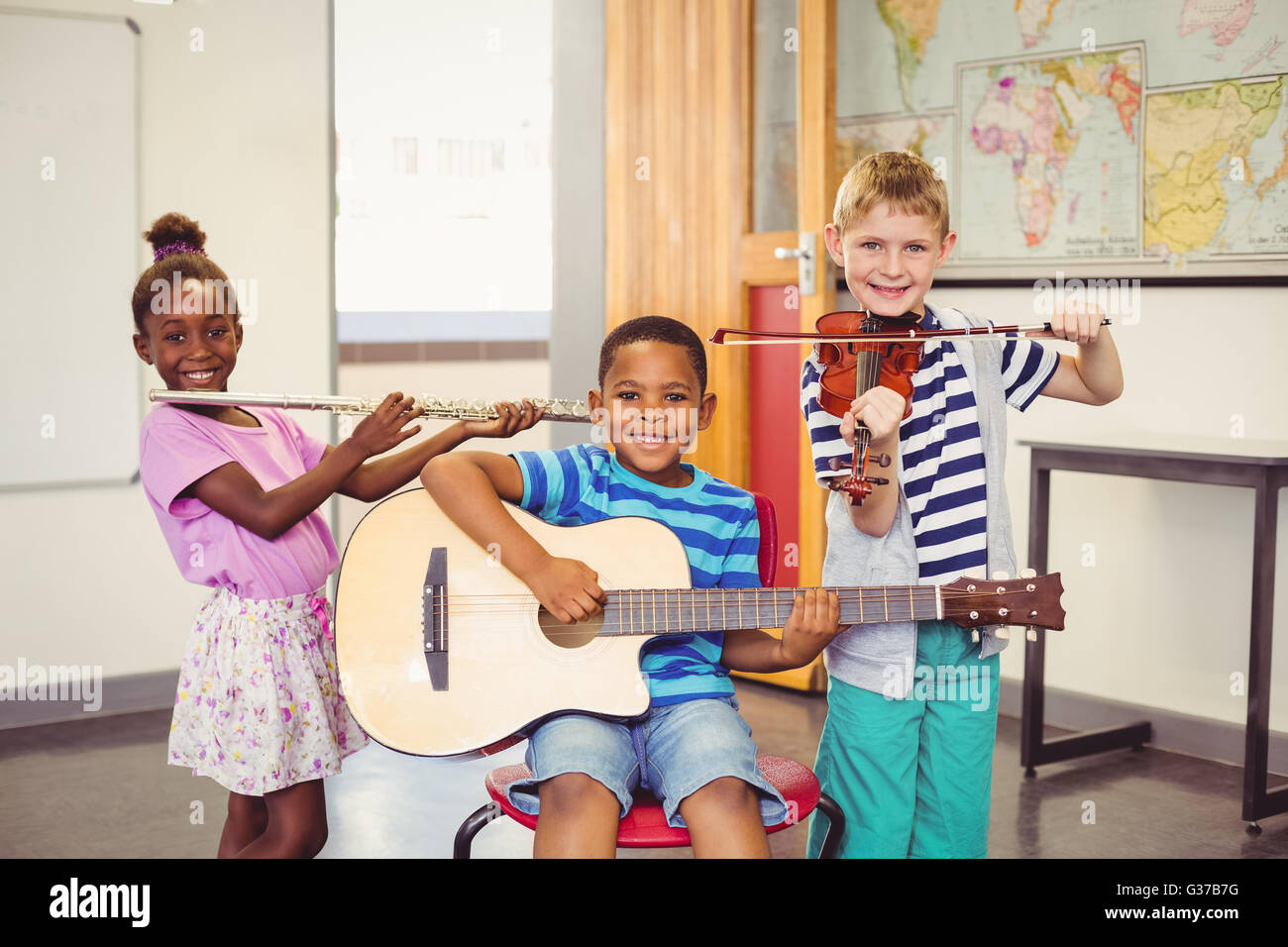 Porträt von lächelnden Kinder spielen Gitarre, Geige, Querflöte im Klassenzimmer Stockfoto