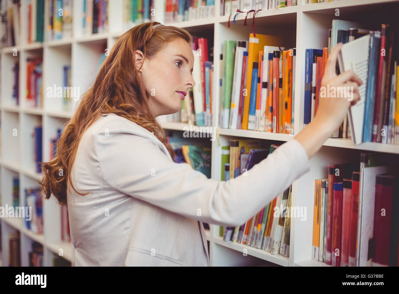 Schullehrer Bücherregal in der Bibliothek ein Buch auswählen Stockfoto