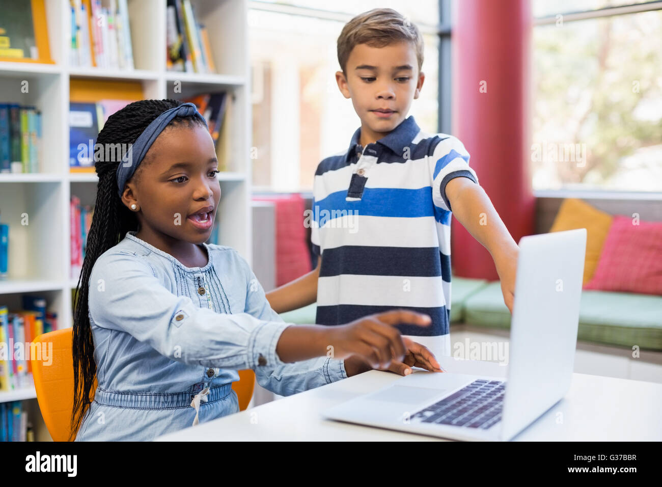 Schülerinnen und Schüler mit einem Laptop in der Bibliothek Stockfoto