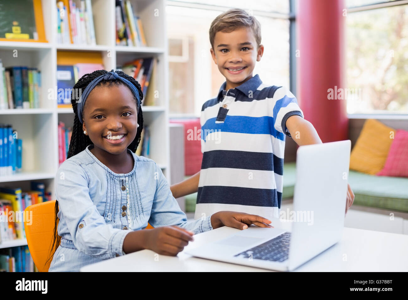 Porträt des Lächelns Schule Kinder mit einem Laptop in der Bibliothek Stockfoto