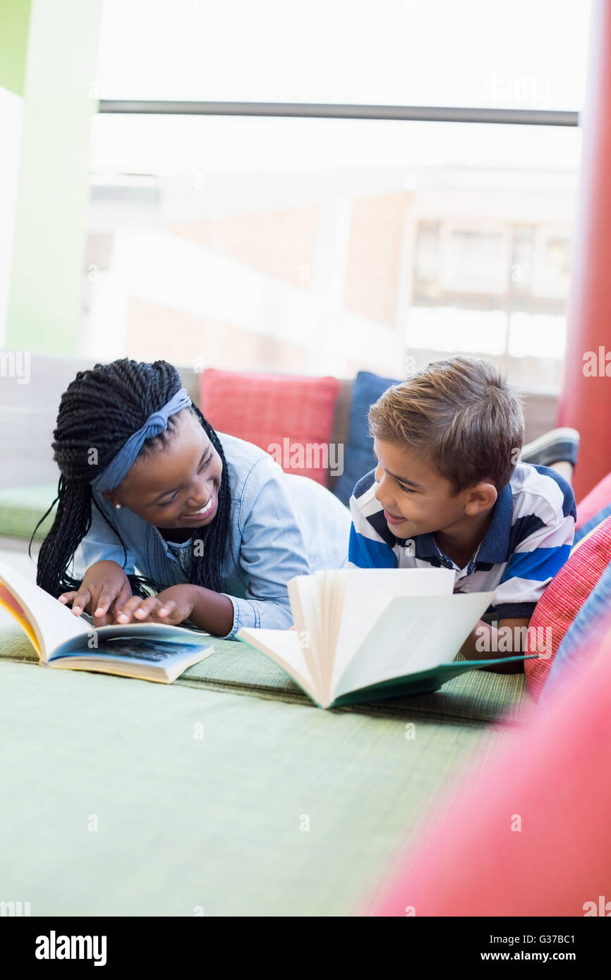 Schülerinnen und Schüler liegen auf Sofa und Lesebuch Stockfoto