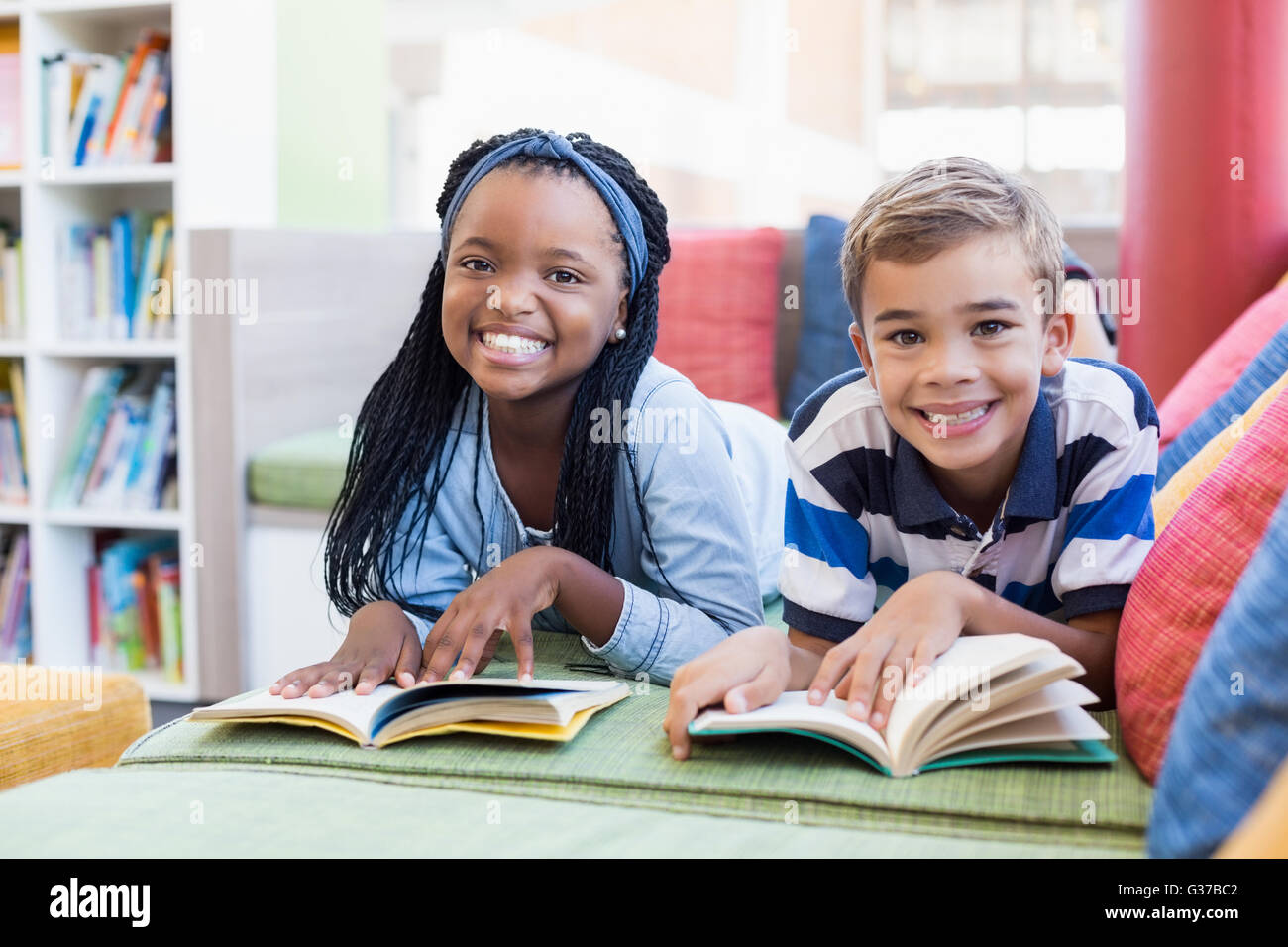 Schülerinnen und Schüler liegen auf Sofa und Lesebuch Stockfoto