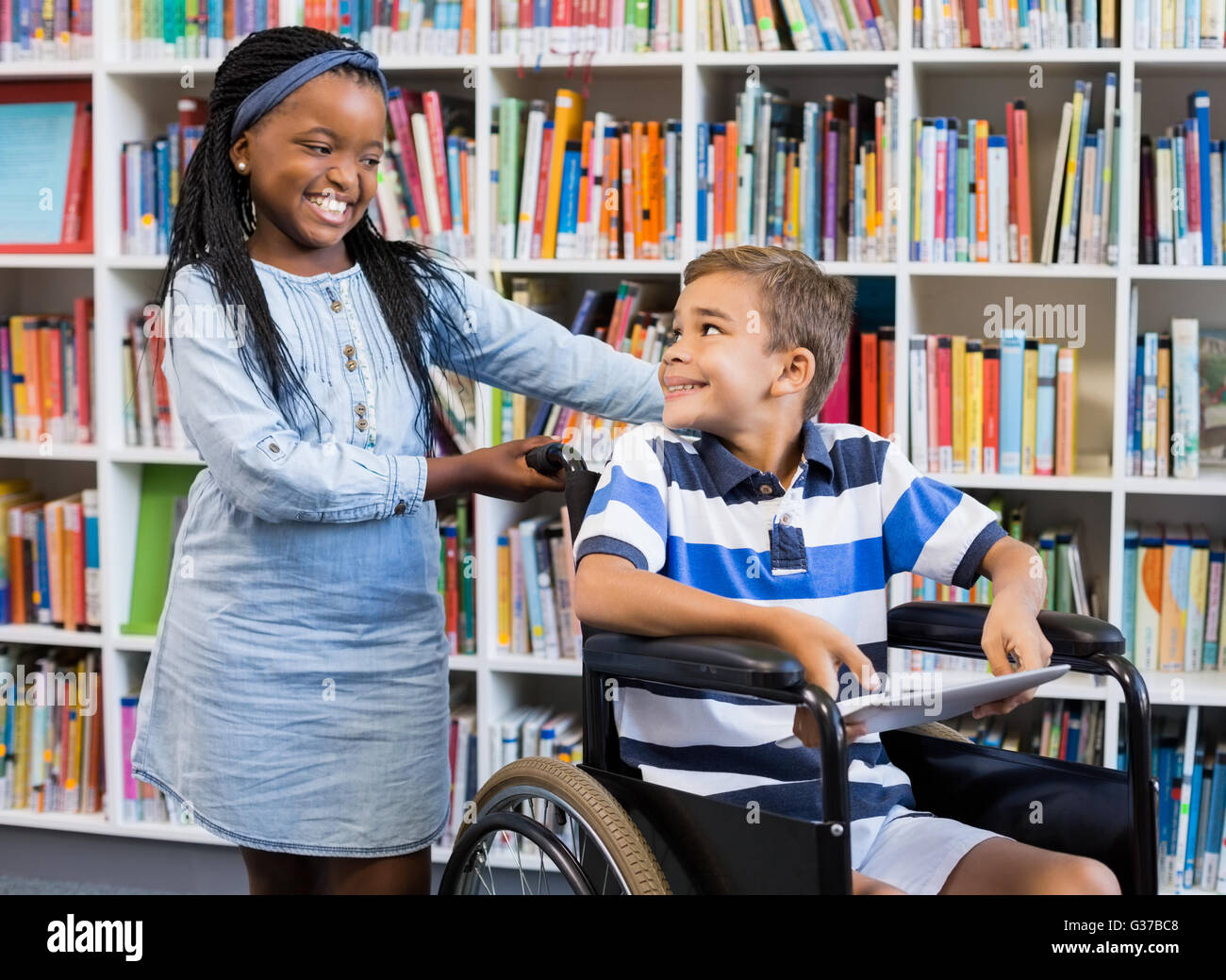 Schulmädchen mit behinderten Jungen im Rollstuhl stehen Stockfoto