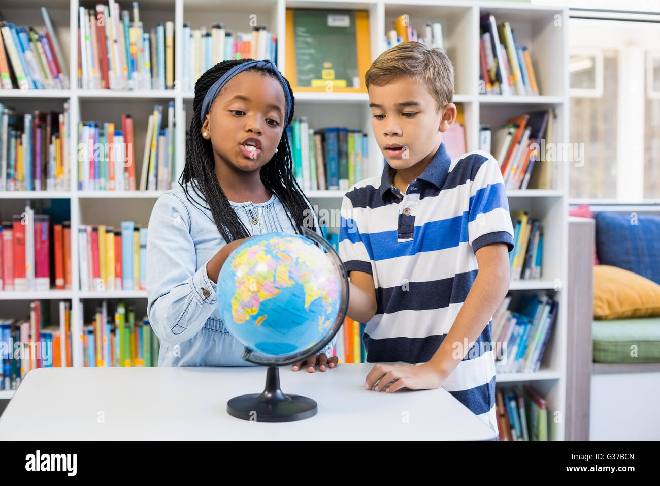 Schulkinder im Globe in Bibliothek suchen Stockfoto