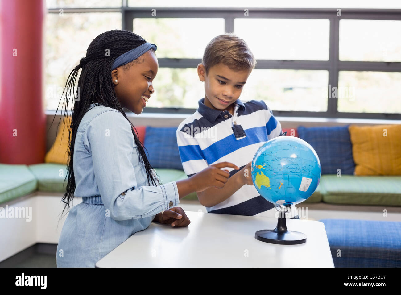 Schulkinder im Globe in Bibliothek suchen Stockfoto