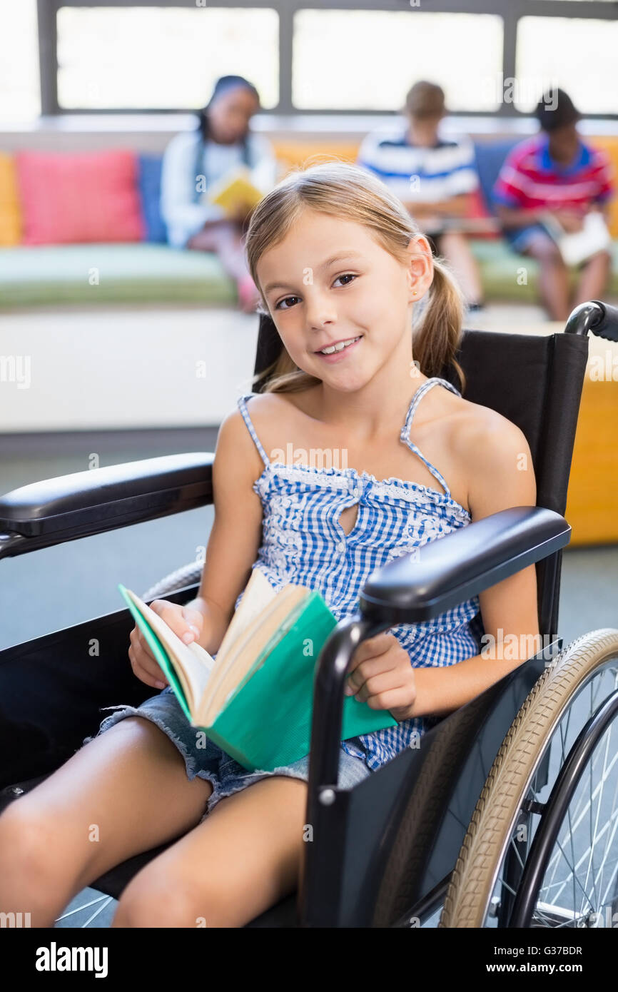Porträt von Behinderten Schule Mädchen Lesebuch in Bibliothek Stockfoto