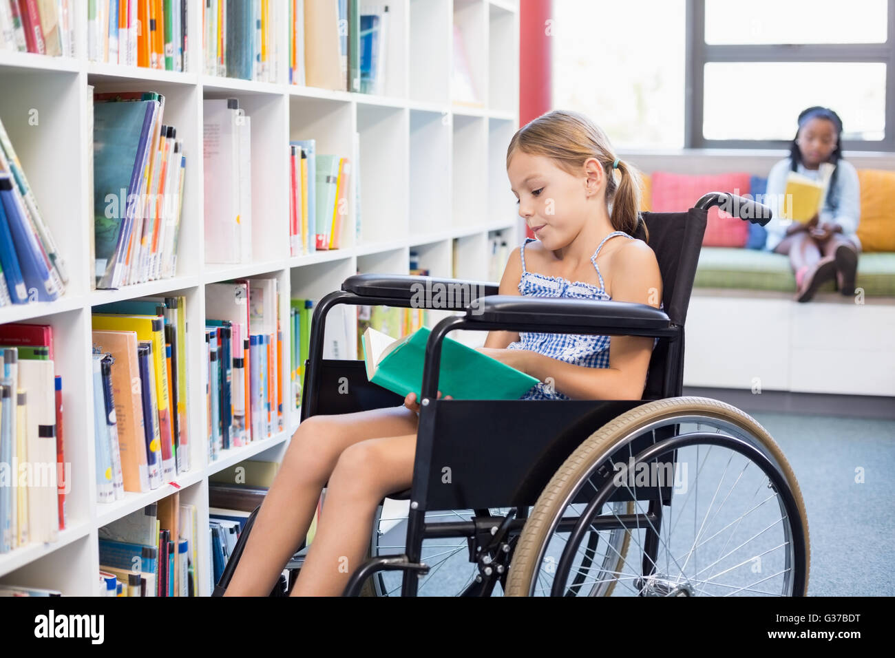 Behinderten Schule Mädchen Lesebuch in Bibliothek Stockfoto