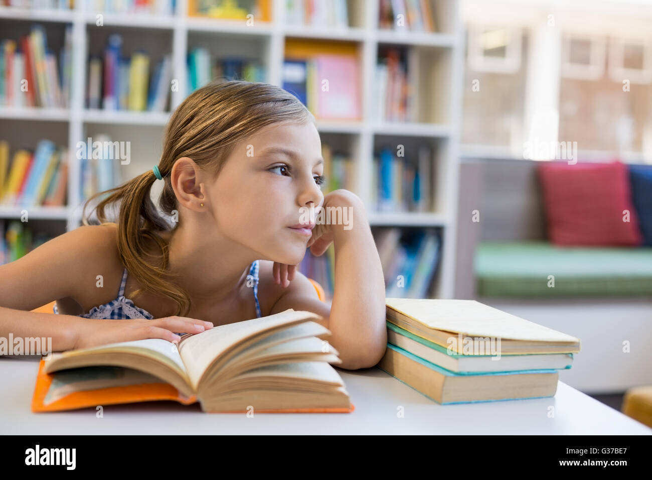 Nachdenklich Schule Mädchen Lesebuch in Bibliothek Stockfoto
