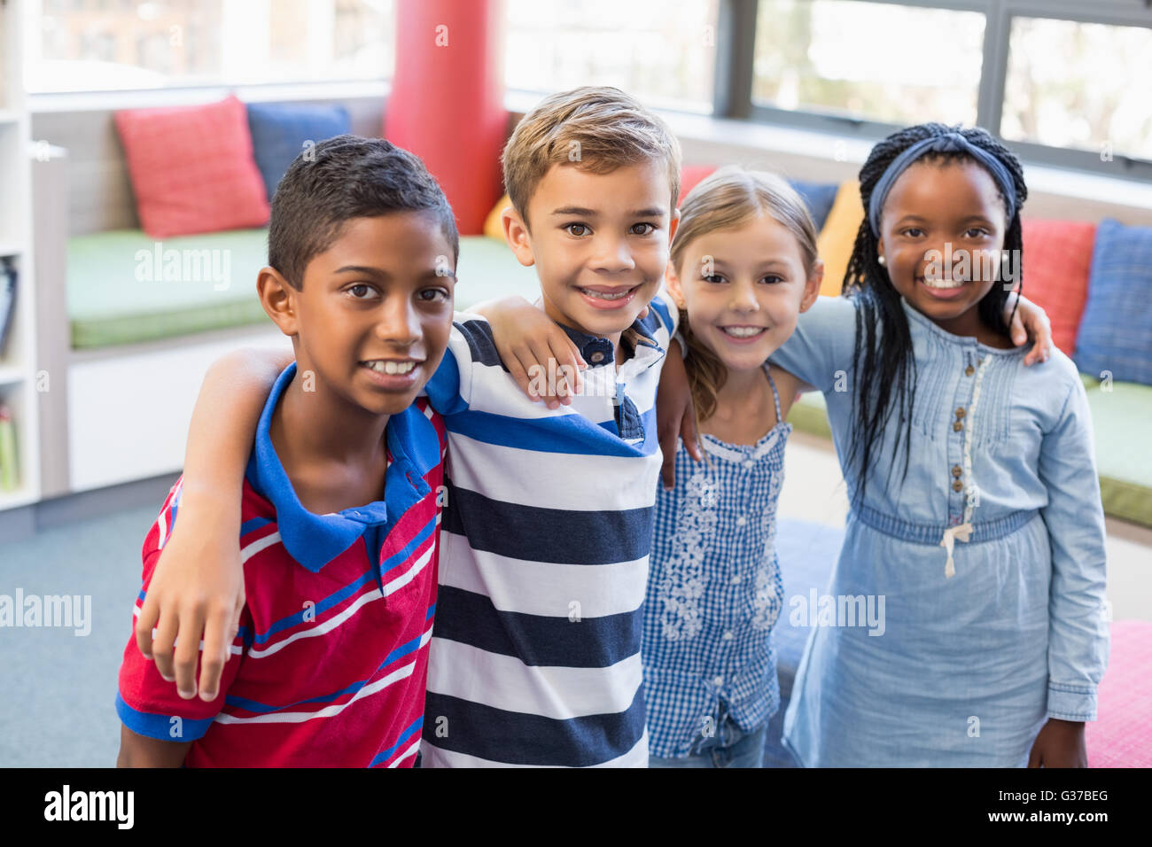 Lächelnd Schule Kinder stehen mit Arm um in Bibliothek Stockfoto