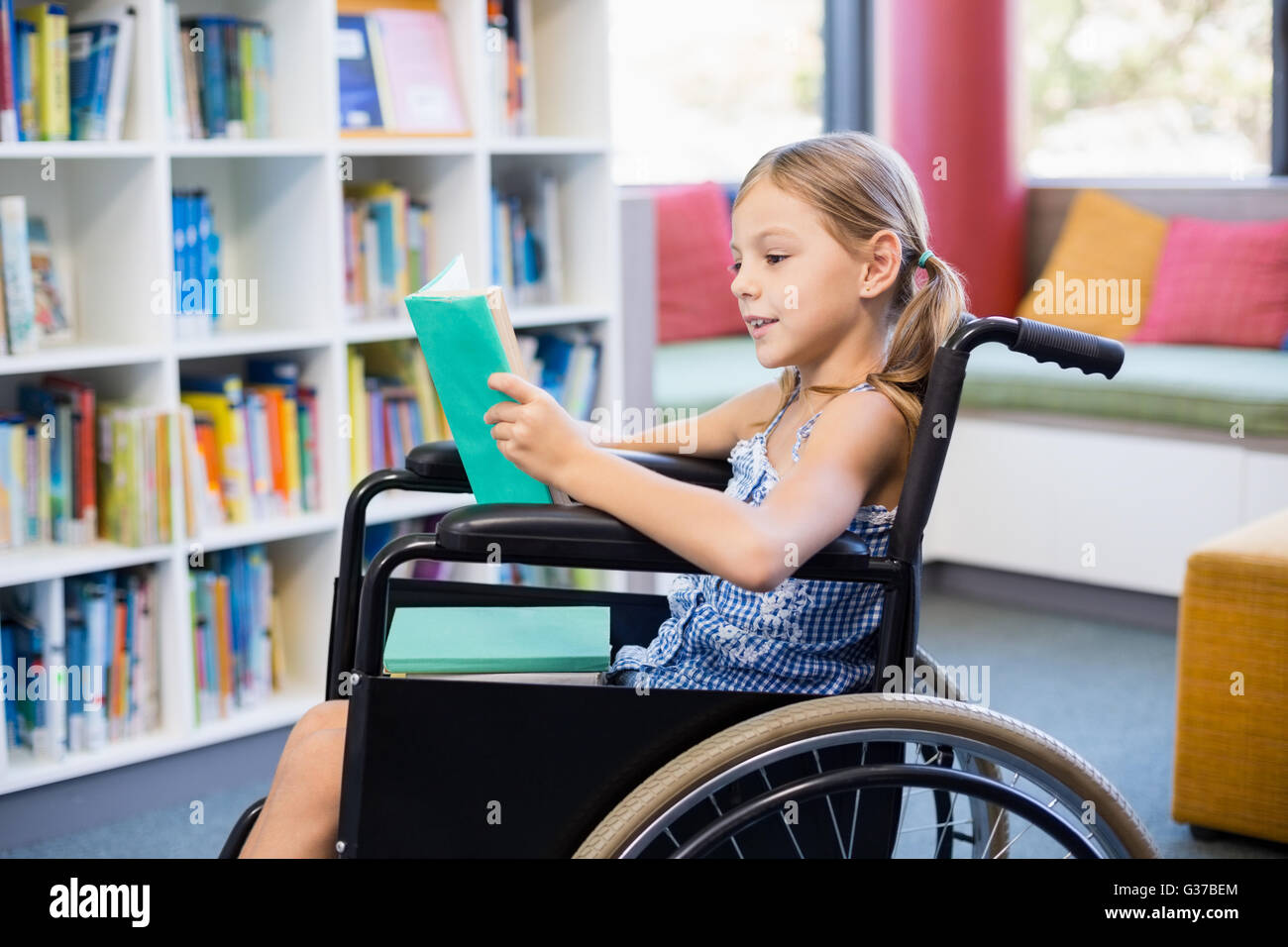 Behinderten Schule Mädchen Lesebuch in Bibliothek Stockfoto