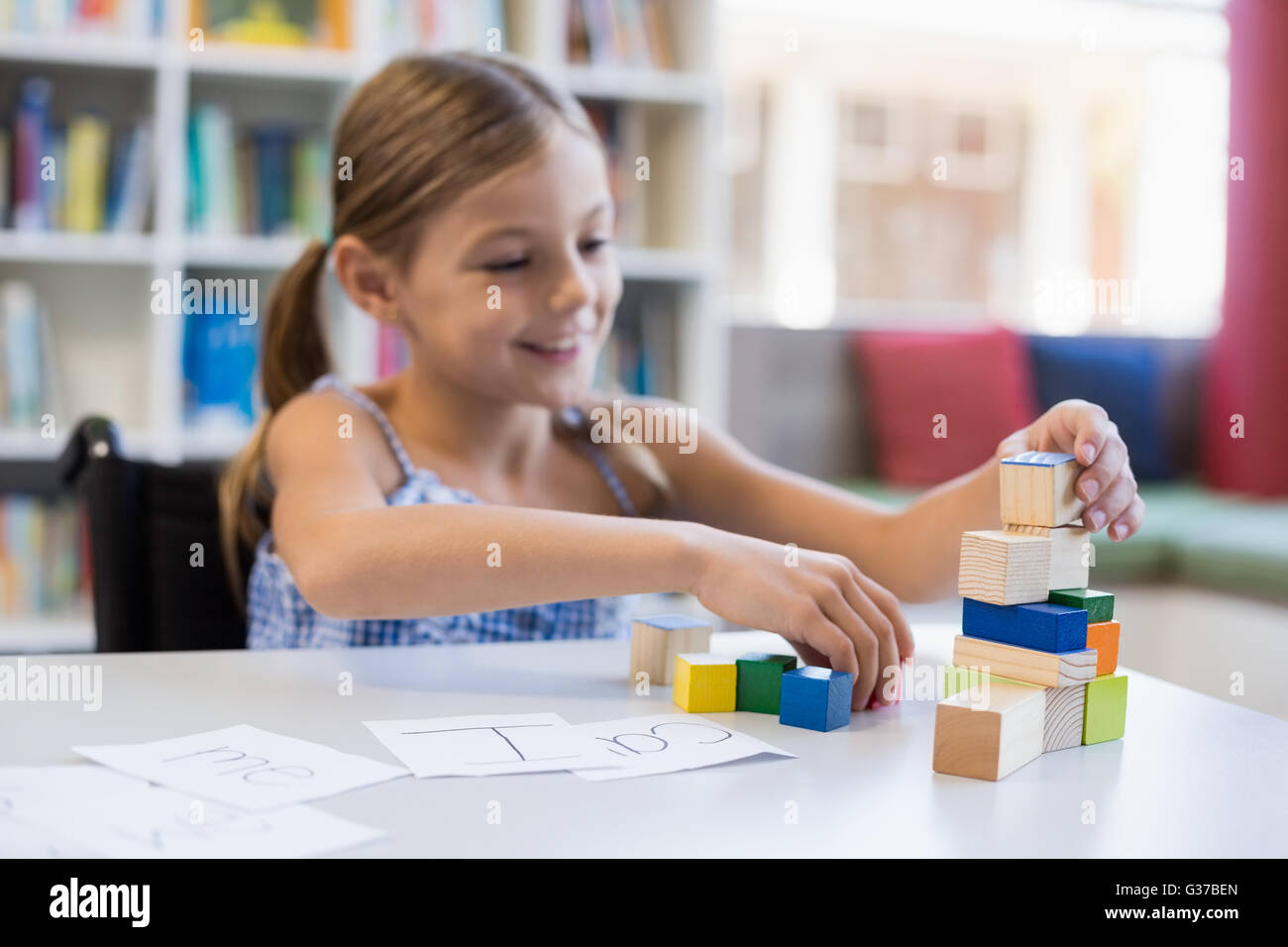 Lächelnde Schulmädchen spielen mit Baustein in der Bibliothek Stockfoto