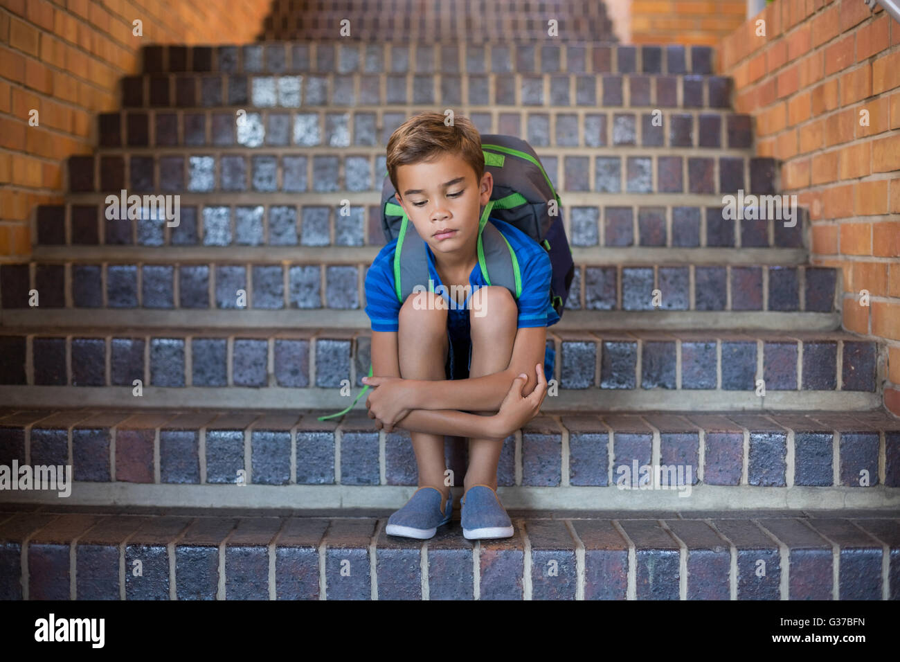 Traurig Schuljunge saß allein im Treppenhaus Stockfoto
