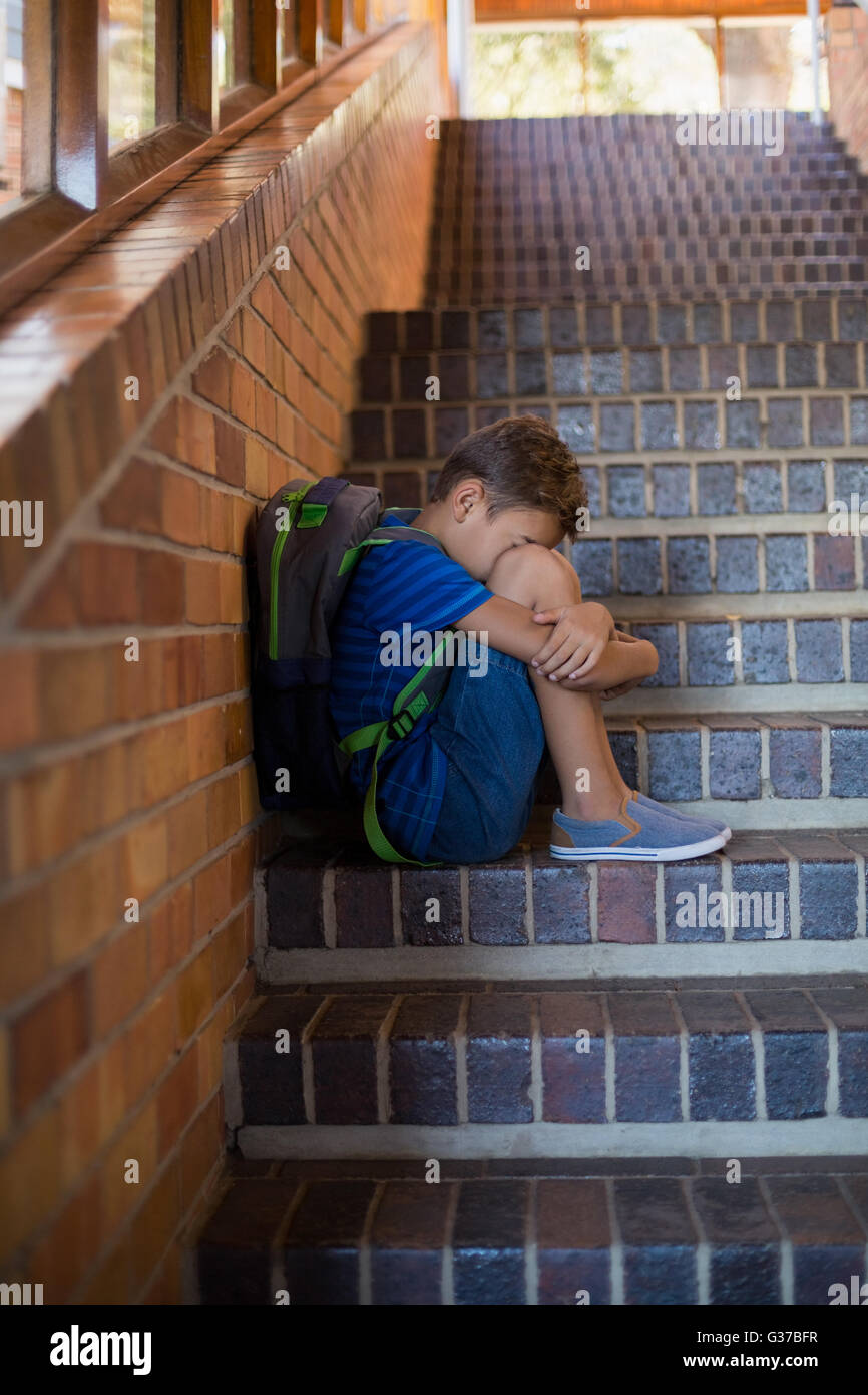 Traurig Schuljunge saß allein auf Treppe Stockfoto