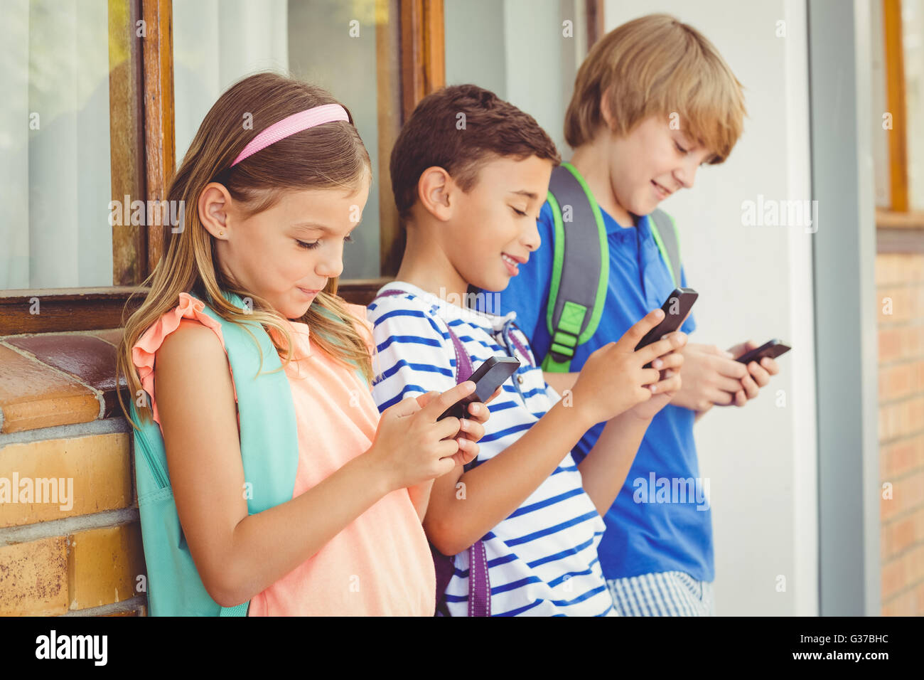 Schulkinder mit Handy im Korridor Stockfoto
