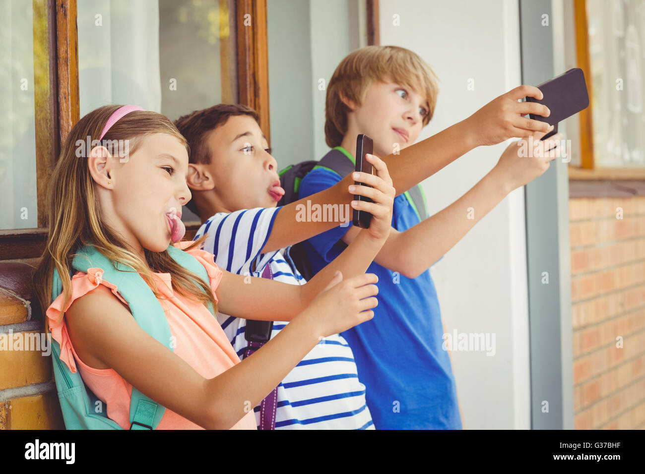 Schulkinder nehmen Selfie mit Handy im Korridor Stockfoto