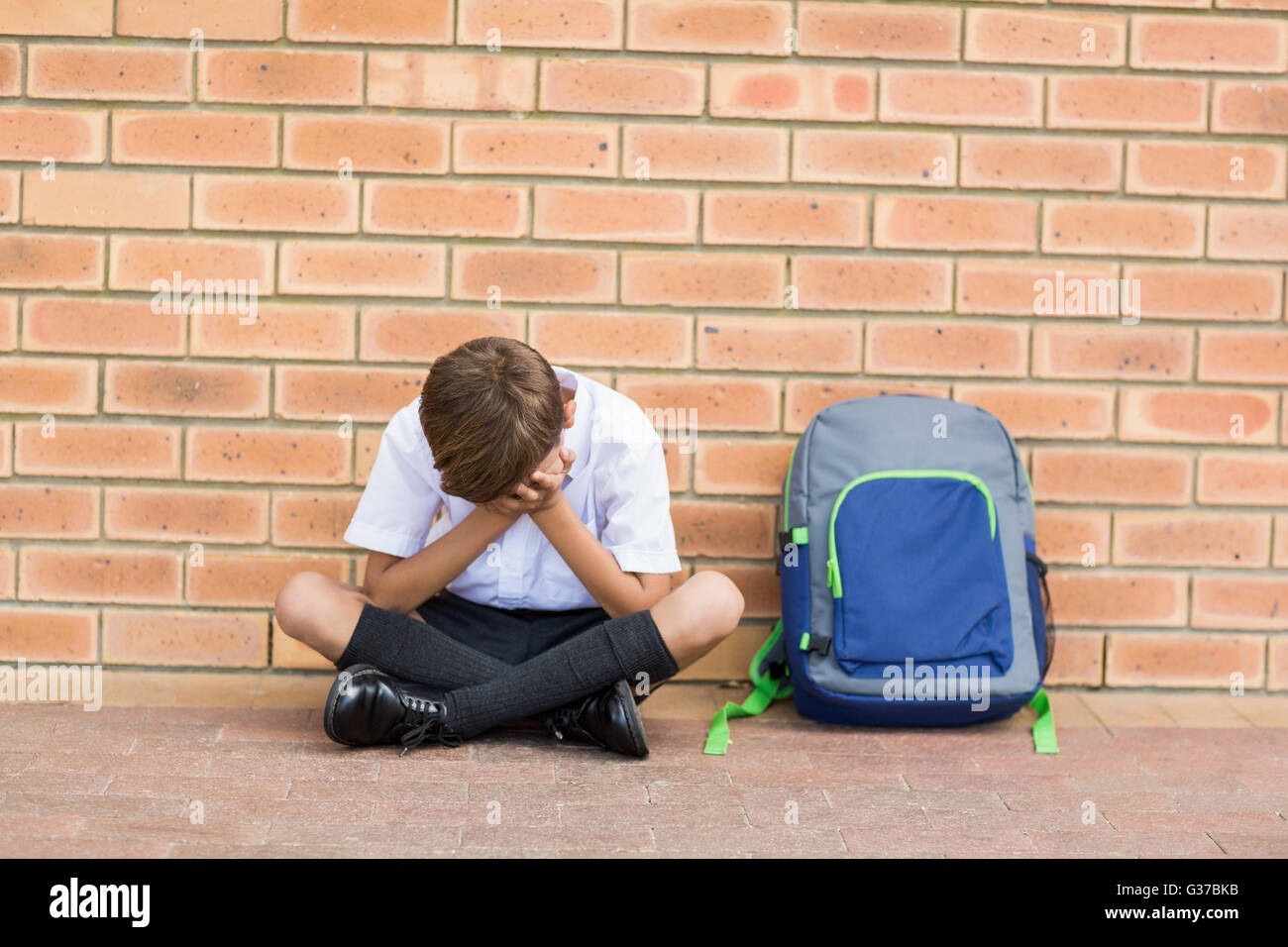 Traurig Schuljunge saß allein im Flur Stockfoto