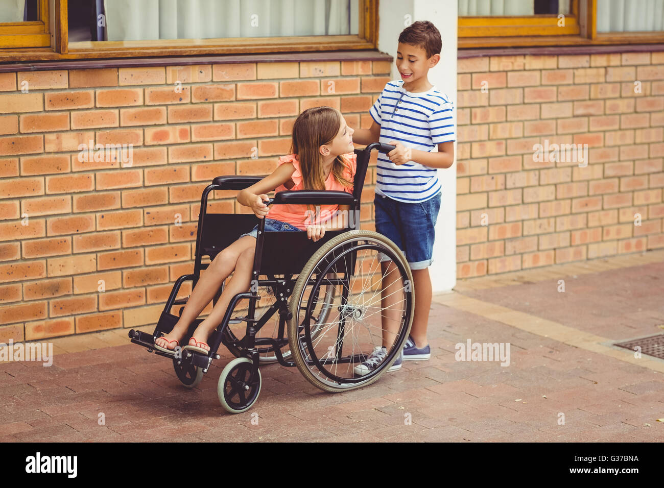 Schüler im Gespräch mit einem Mädchen im Rollstuhl Stockfoto