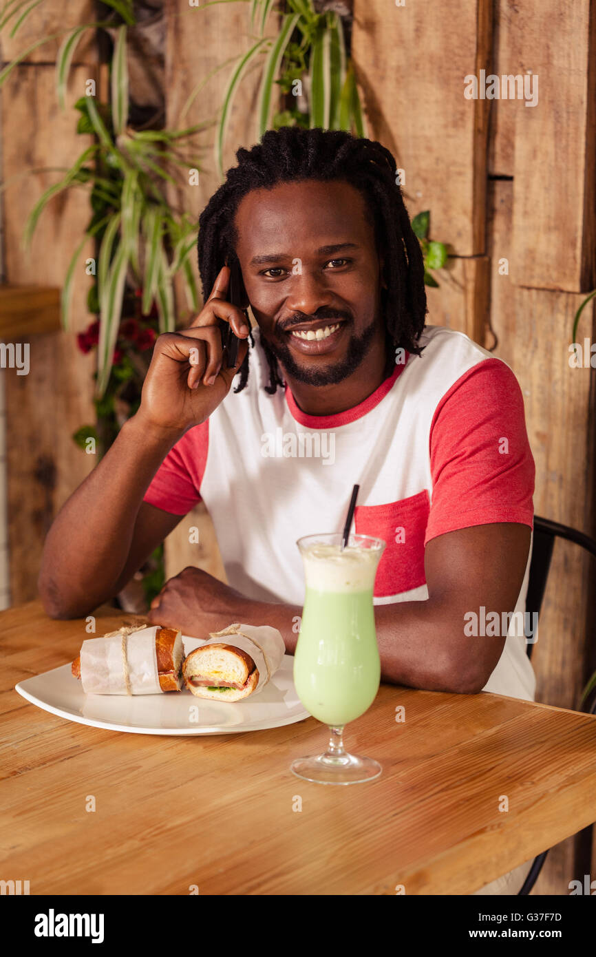 Hipster-Mann am Telefon während des Essens Stockfoto