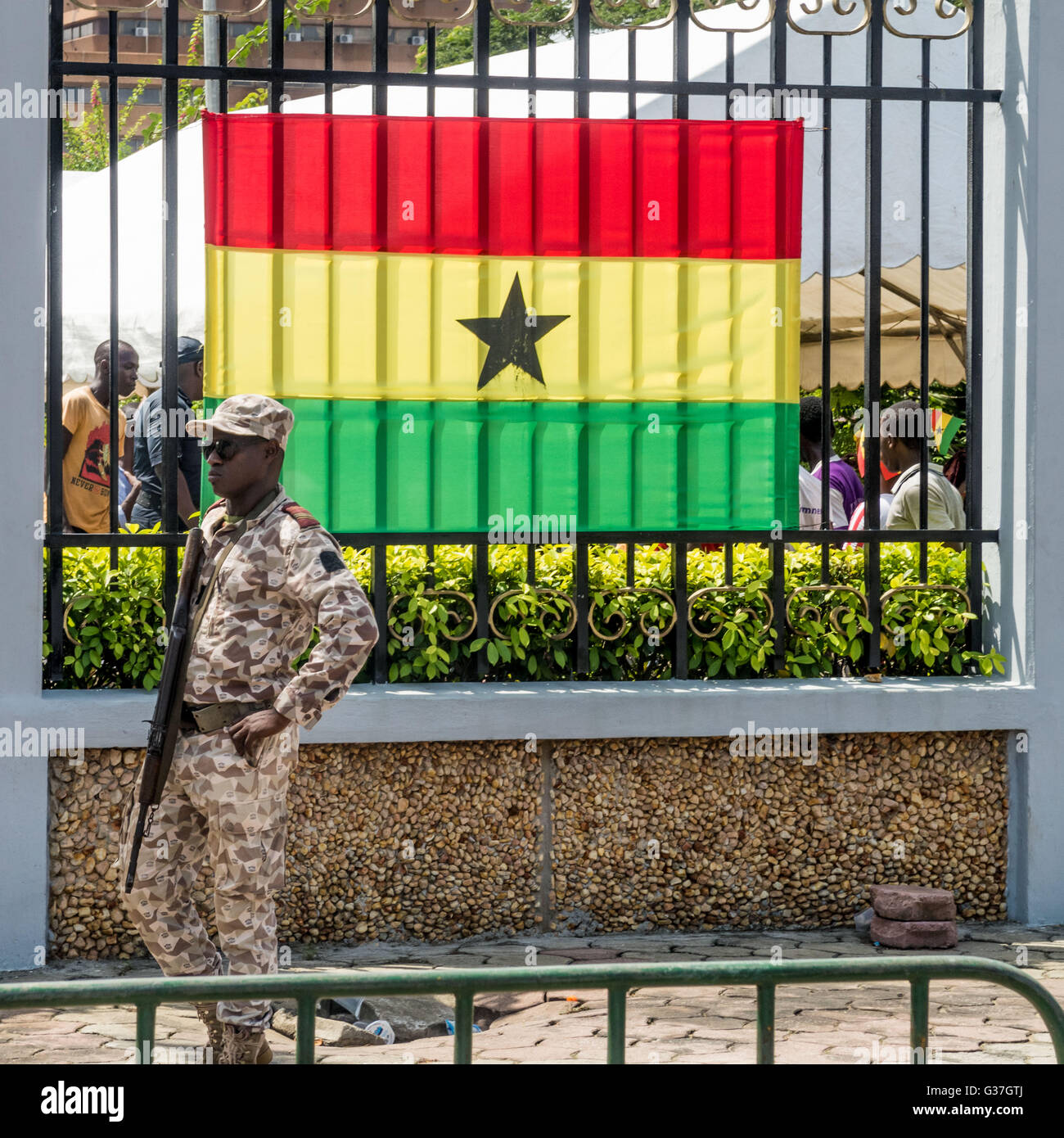 Bewaffnete Wache steht neben der Flagge von Ghana in Abidjan, Elfenbeinküste Stockfoto