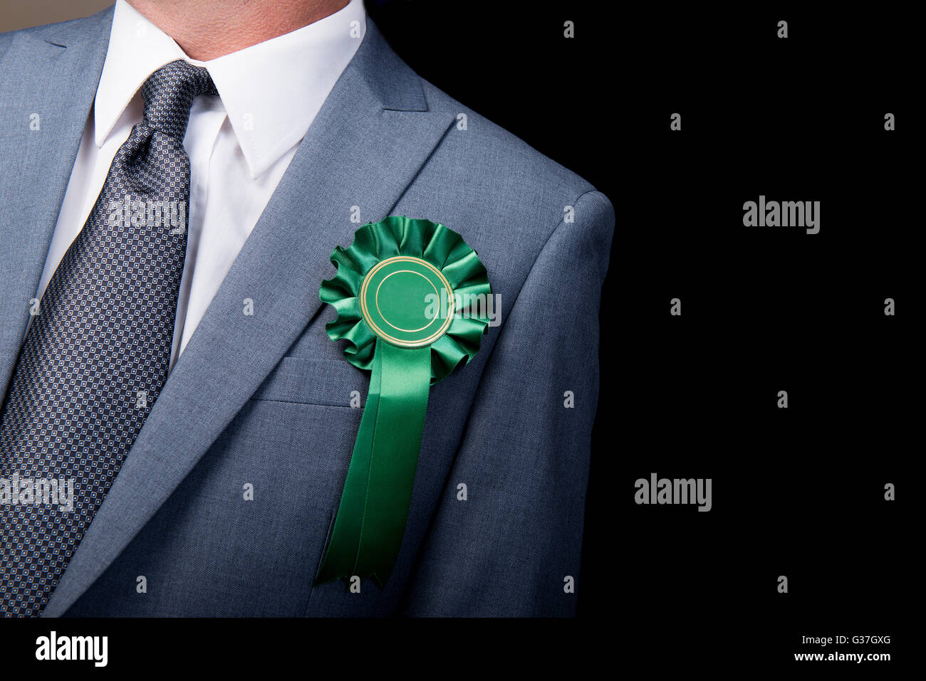 Kopf und Schultern Ansicht des Wahl-Kandidaten tragen eine grüne Rosette vor einem schwarzen Hintergrund. Stockfoto