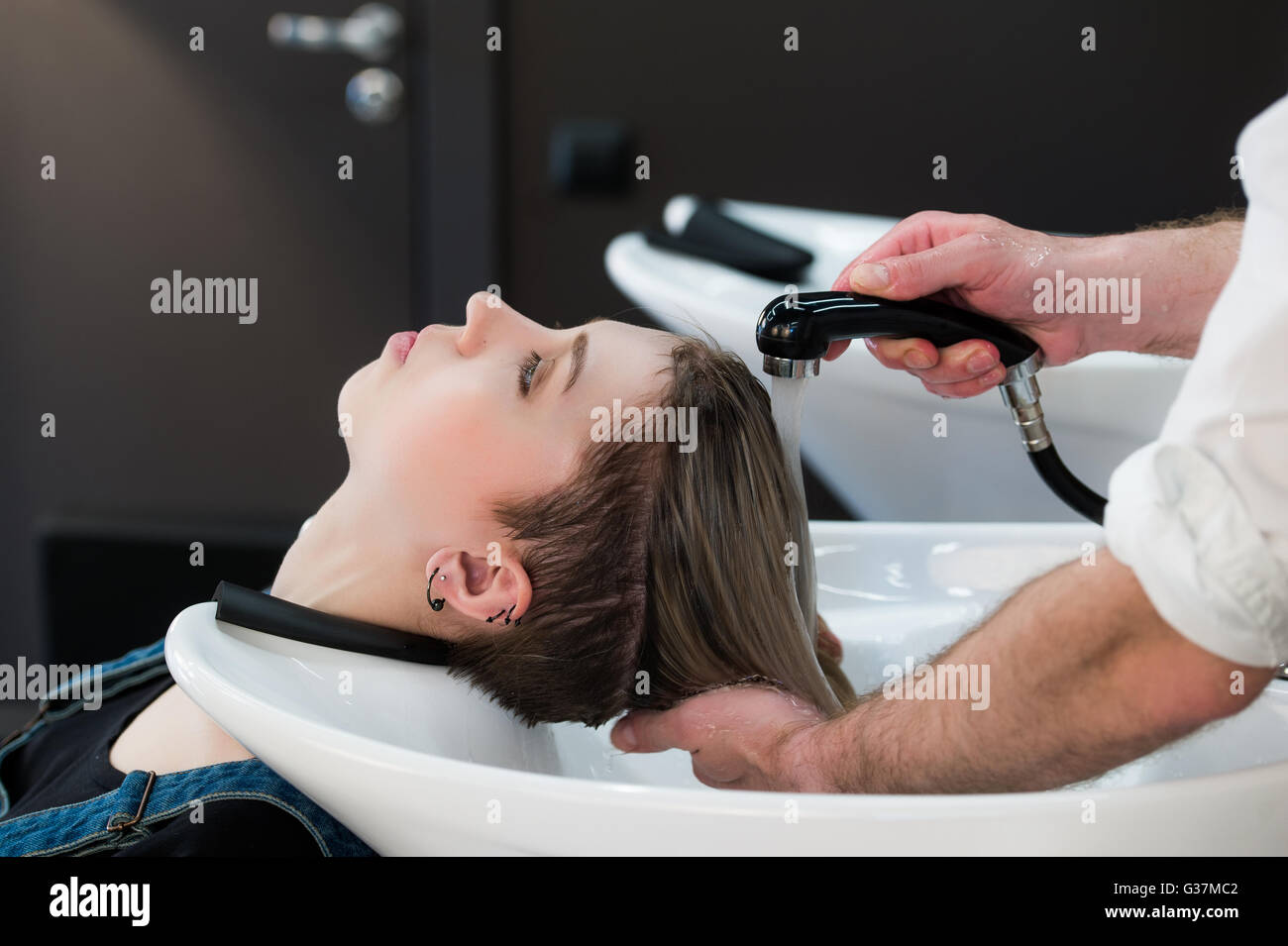 Junge Teenager-Mädchen im Friseursalon Haare durch männliche Friseur Hände waschen. Stockfoto