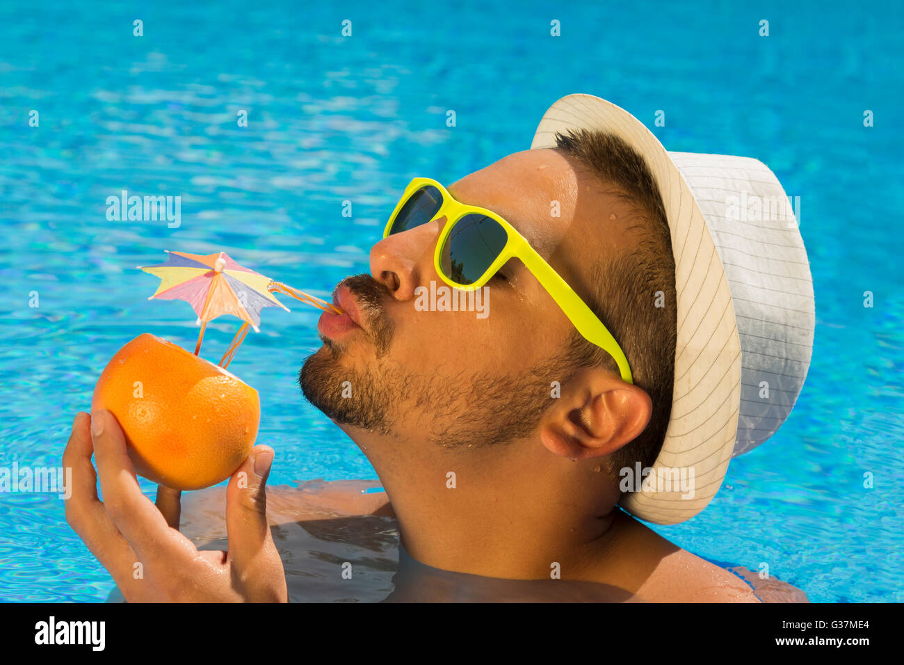 Junge Kerl trinken frischen Grapefruitsaft im Schwimmbad Stockfoto