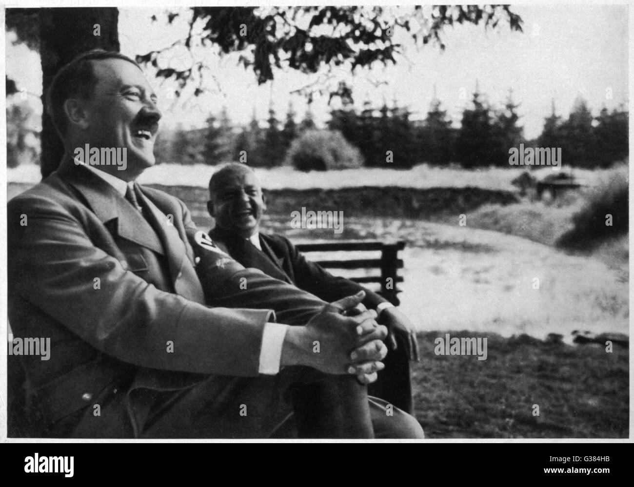 Deutscher Politiker und Führer, Adolf Hitler (1889-1945), auf einer Bank sitzt und lacht mit einem Kollegen.     Datum: 1935 Stockfoto