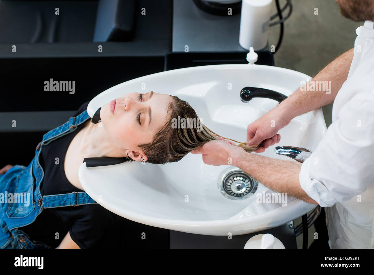 Haarpflege im modernen Spa-Salon. Männliche Friseur Teen Mädchen Haare waschen Stockfoto