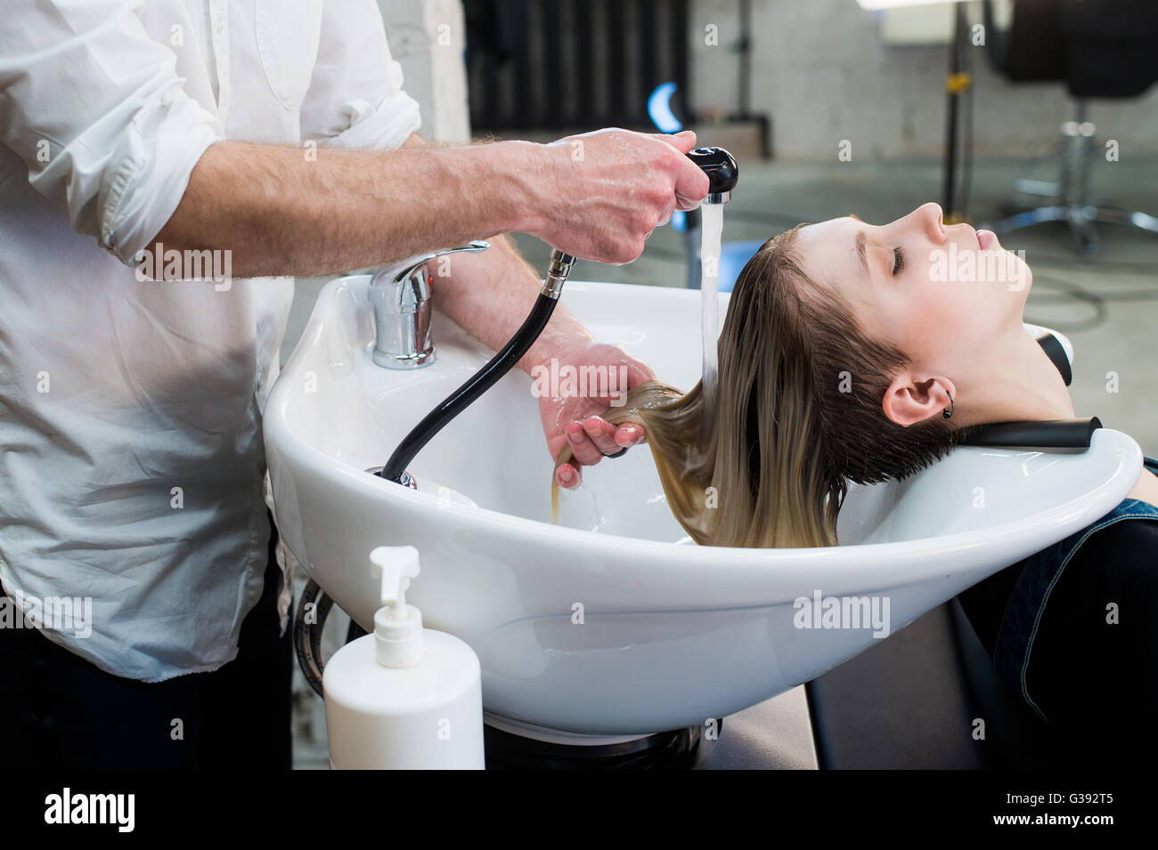 Junge Teenager-Mädchen im Friseursalon Haare durch männliche Friseur Hände waschen. Stockfoto