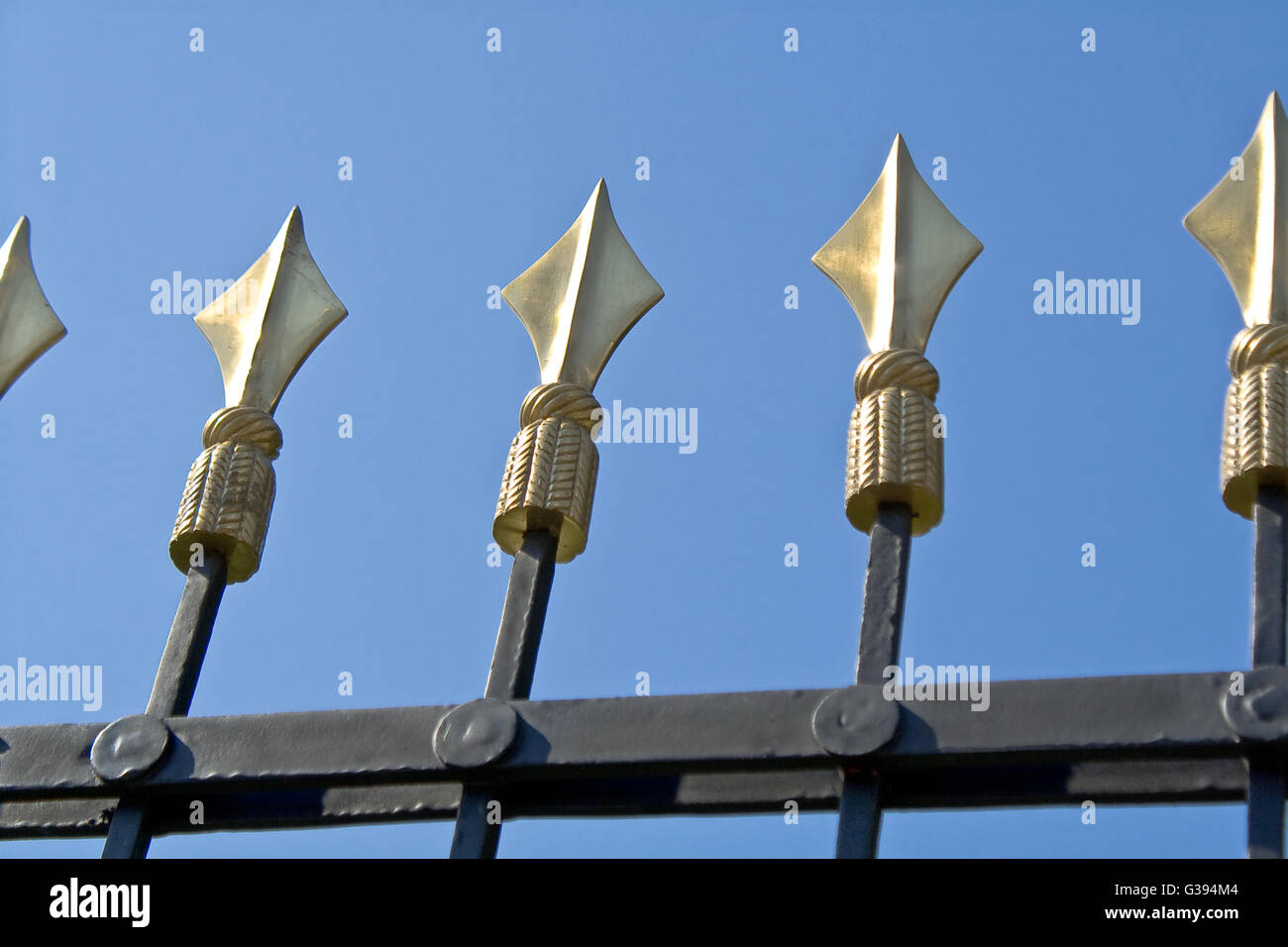Golden Spikes auf Eisenzaun über blauen Himmel Stockfoto