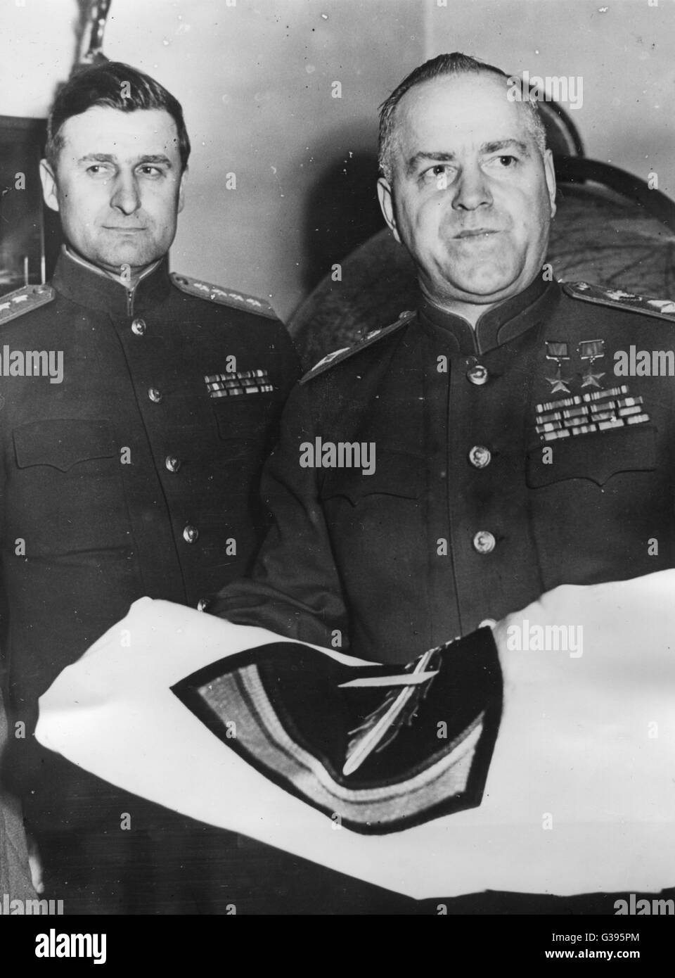 Fangen Sie Marschall Georgy K. Zhukov (rechts), Stellvertretender Oberbefehlshaber für alle sowjetischen Streitkräfte und General Vasily Sokolovsky (links) (1897 – 1968), Stabschef von Marschall Zhukov, nach Erhalt der SHEF Emblem Flagge, Geschenk von General Eisenhower, Oberster Alliierter Befehlshaber. Stockfoto