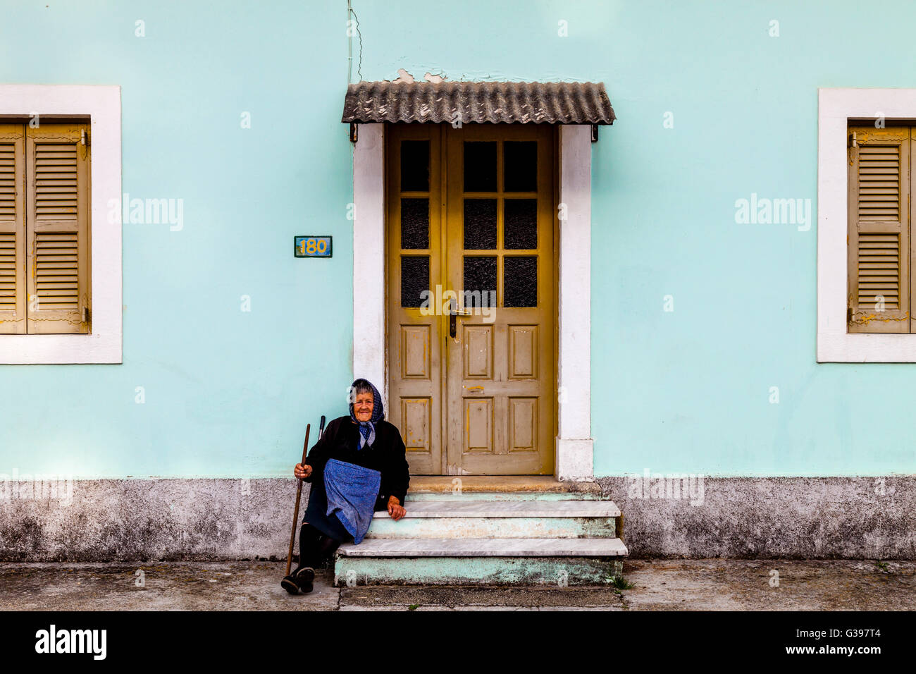 Eine ältere griechische Frau sitzt vor ihrem Haus, Sidari, Korfu, Griechenland Stockfoto