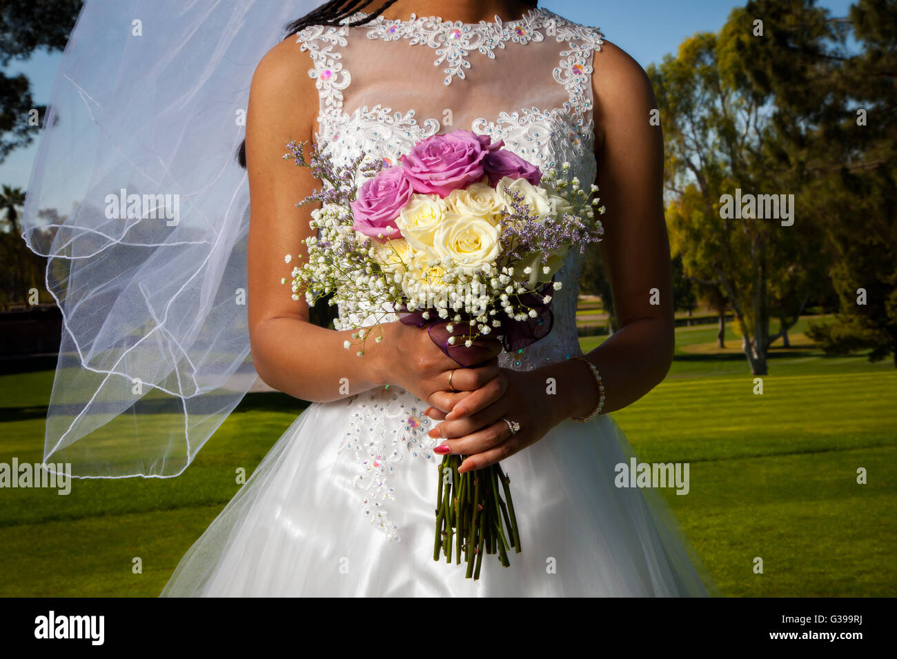 Detail-Bild von einem afroamerikanischen Braut hält ihre rose Bouquet vor ihr.  Ihr Schleier weht sanft im Wind. Stockfoto