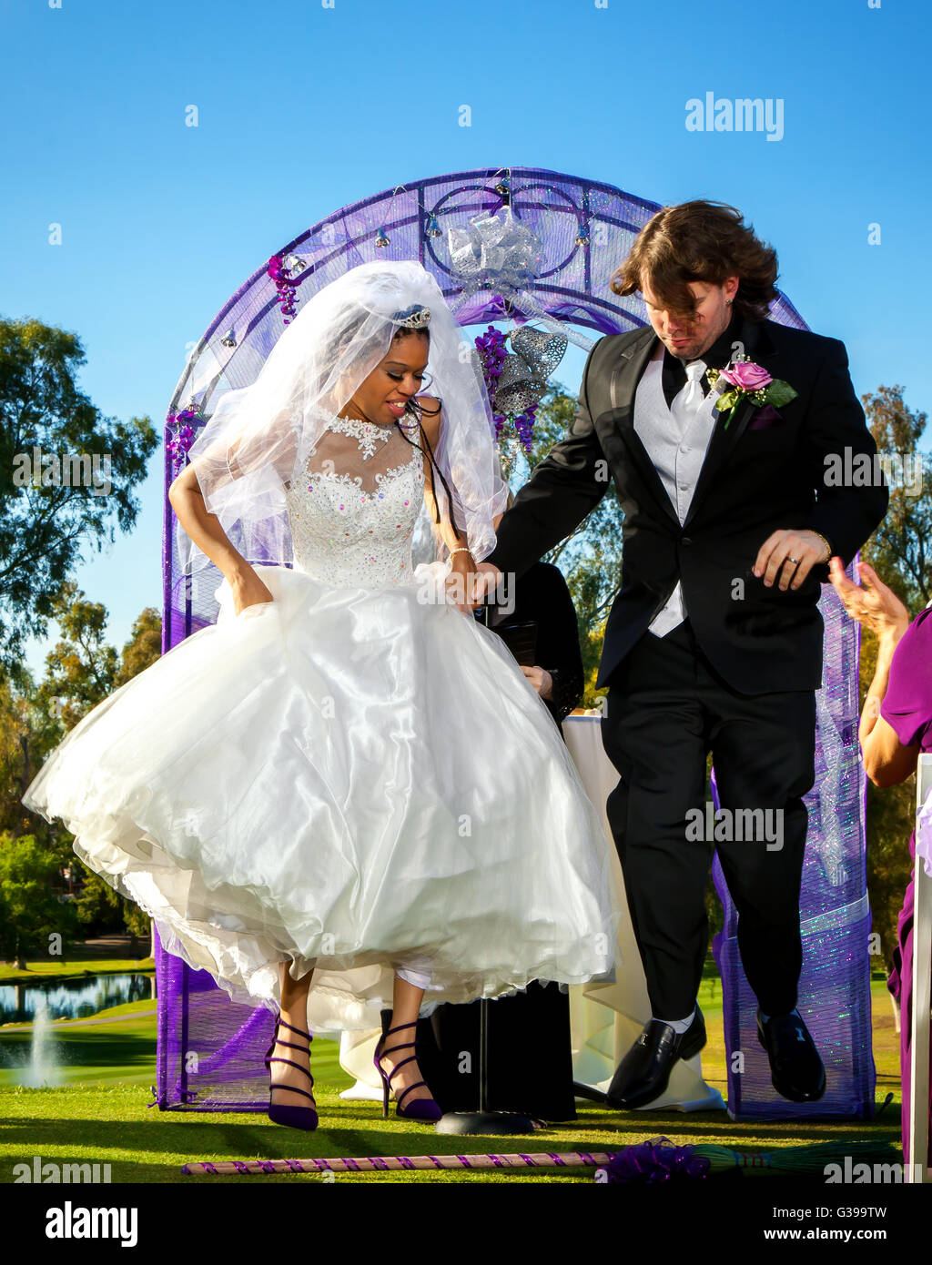 Eine Braut und Bräutigam springen des Besens als Teil ihrer Hochzeitszeremonie. Stockfoto