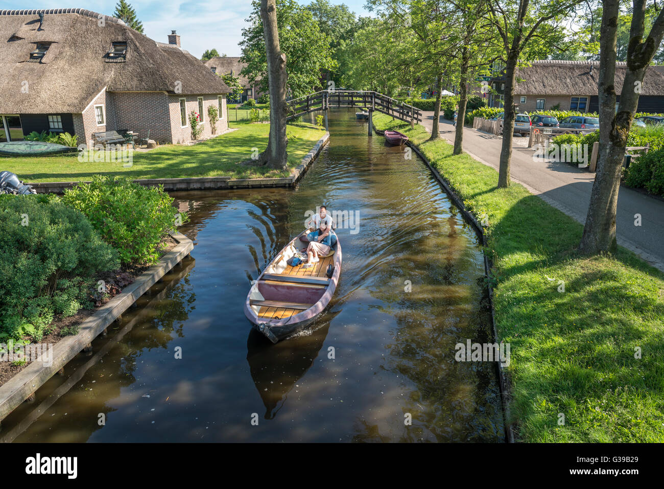 Giethoorn, Niederlande. Elektroboot im Dorpsgracht oder im Dorf Kanal mit romantischen jungen chinesischen Ehepaar im Juni. Stockfoto