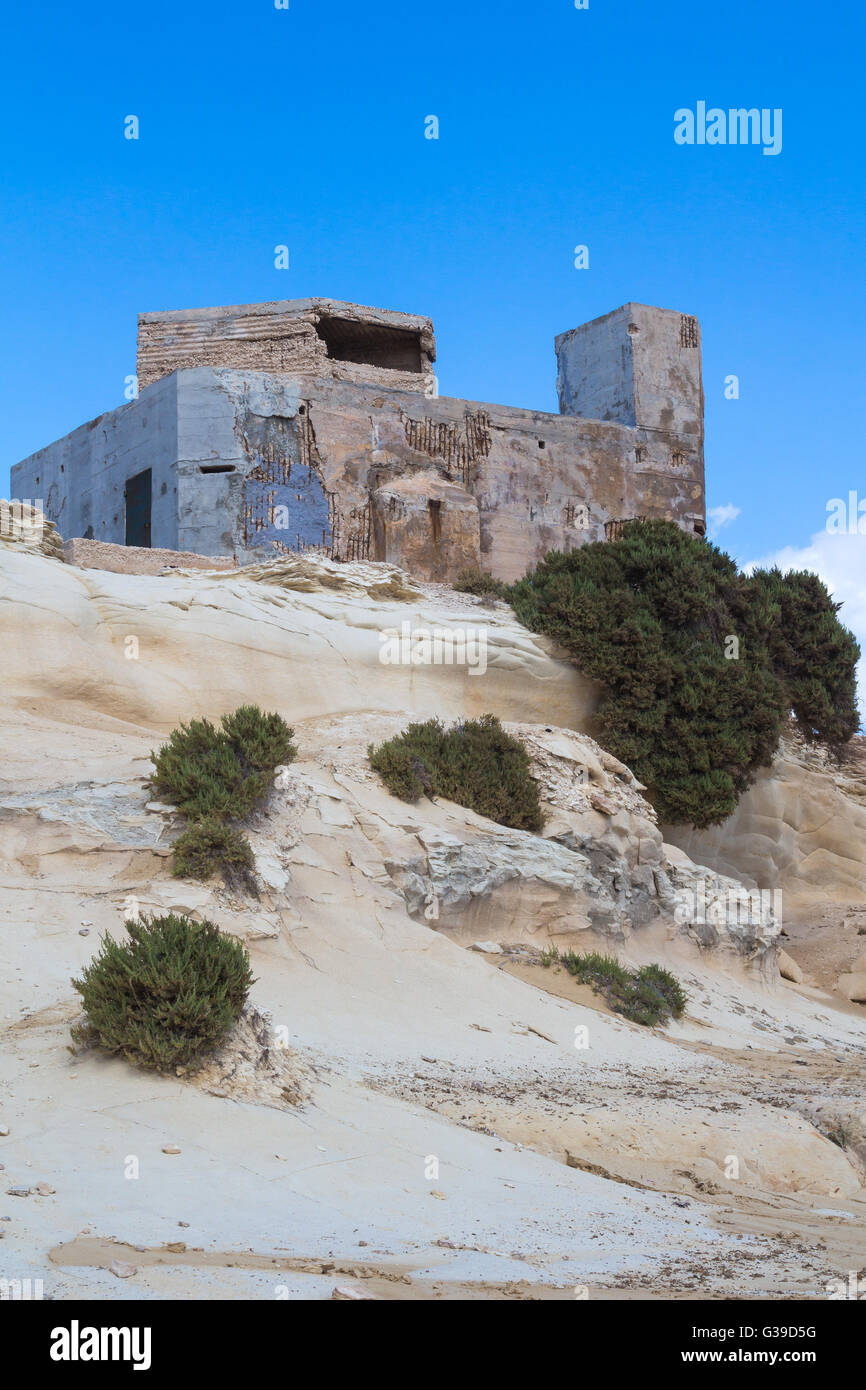Sand Farbe der Felsen mit geschwungener Form und ein altes Gebäude. Küste der Insel Malta, Stadt Marsaskala. Blauer Himmel mit einigen whi Stockfoto