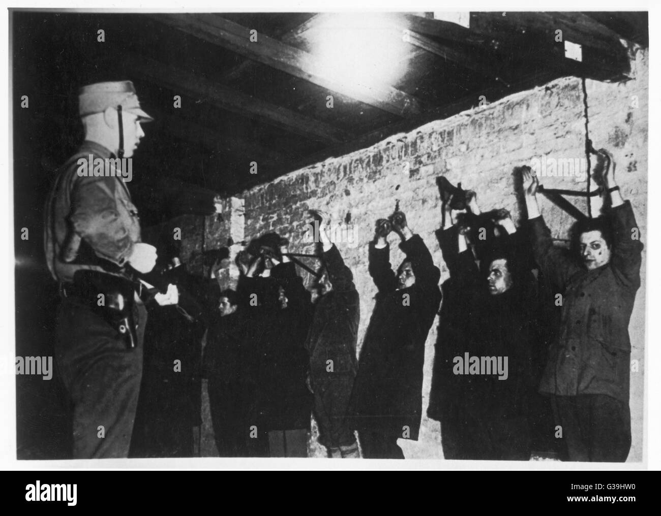 Politische Gefangene mit erhobenen Armen sind gegen eine Wand mit vorgehaltener Waffe gefüttert und gehalten von der SA.       Datum: Januar 1933 Stockfoto