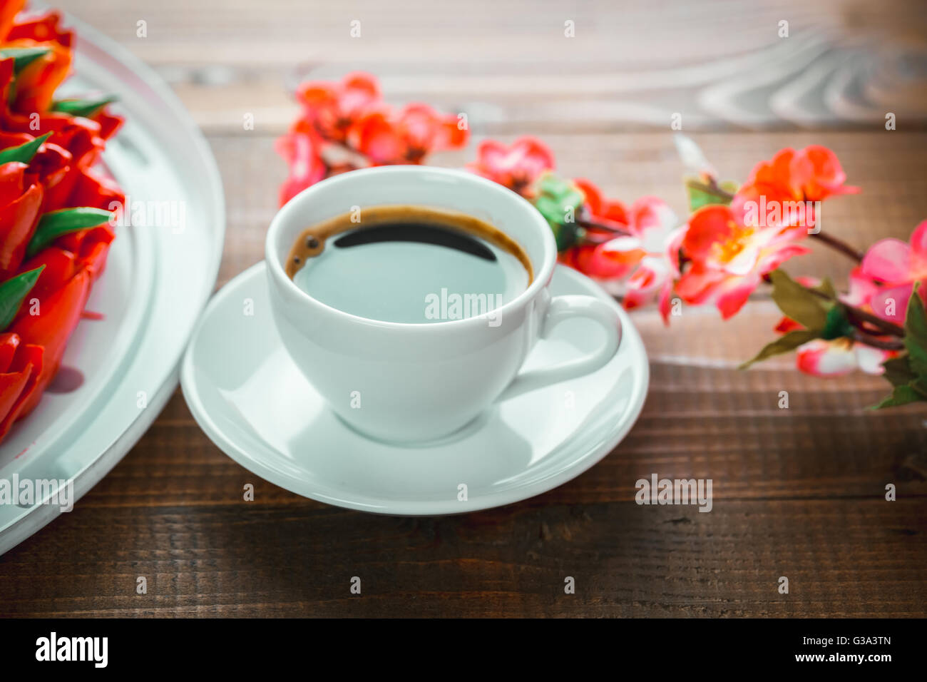 Schönen Hintergrund mit einer Tasse heißen Kaffee mit Schaum und eine Geburtstagstorte mit Blumen auf Holz- Hintergrund Stockfoto