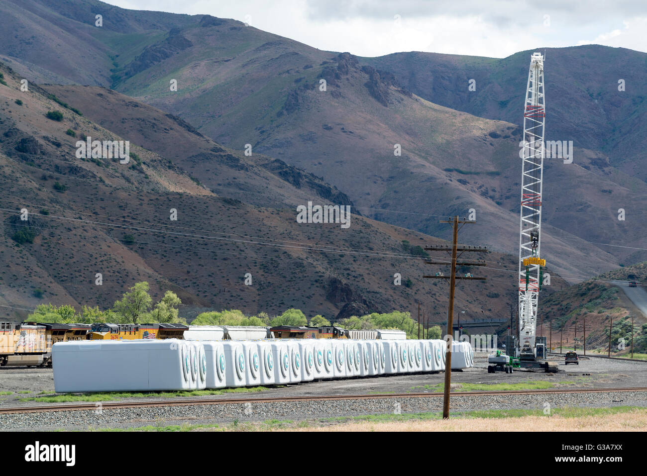 Reihe von Windkraftanlagen abgeladen aus einem Zug mit einem Kran in einem Railyard in Huntington, Oregon. Stockfoto