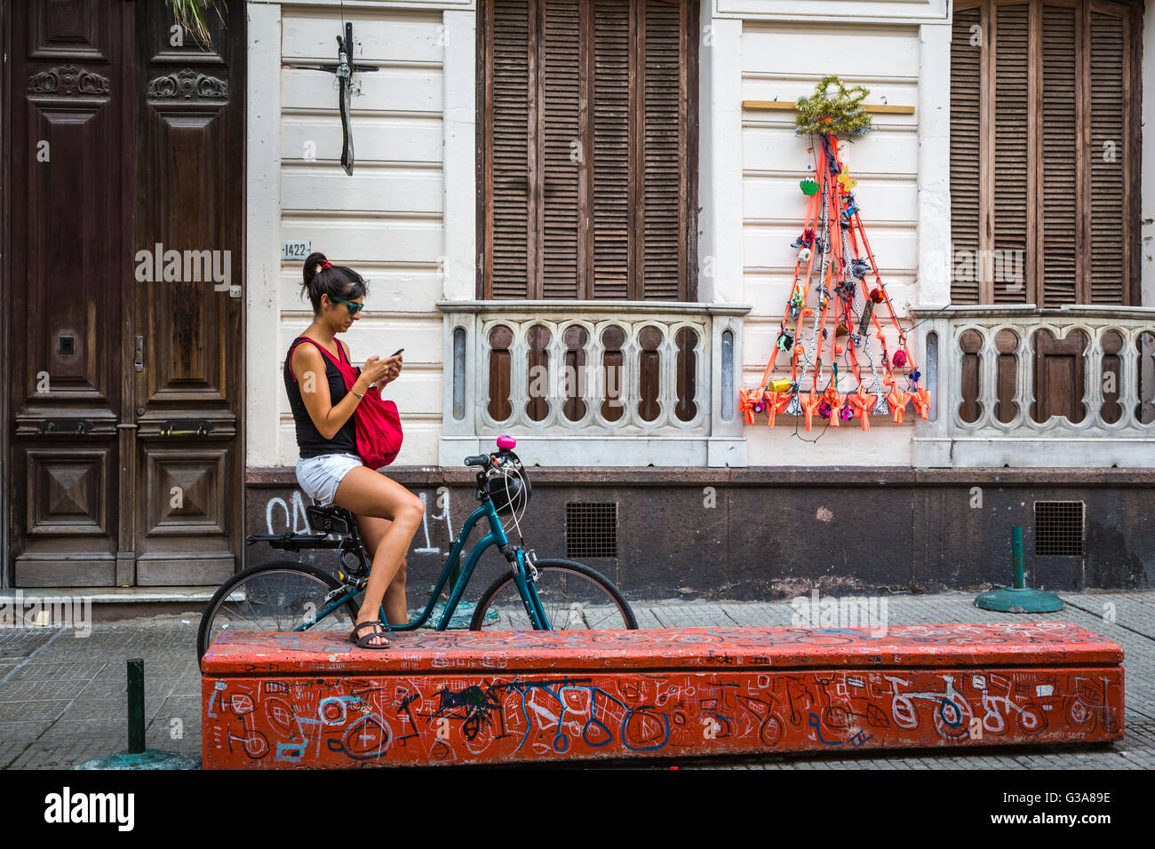 Eine junge Dame mit ihrem Fahrrad überprüft ihr Handy in Montevideo, Uruguay, Südamerika. Stockfoto