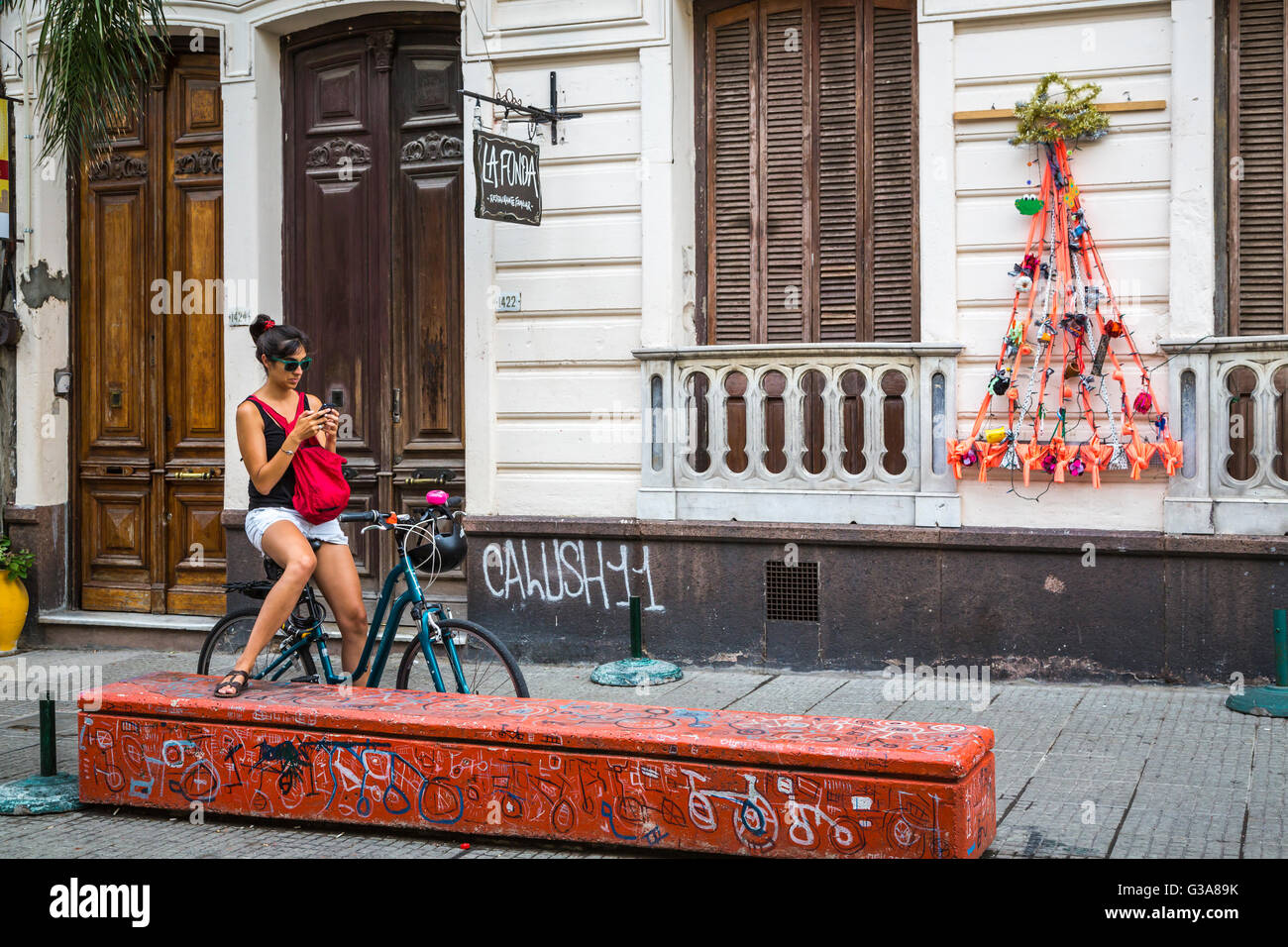 Eine junge Dame mit ihrem Fahrrad überprüft ihr Handy in Montevideo, Uruguay, Südamerika. Stockfoto